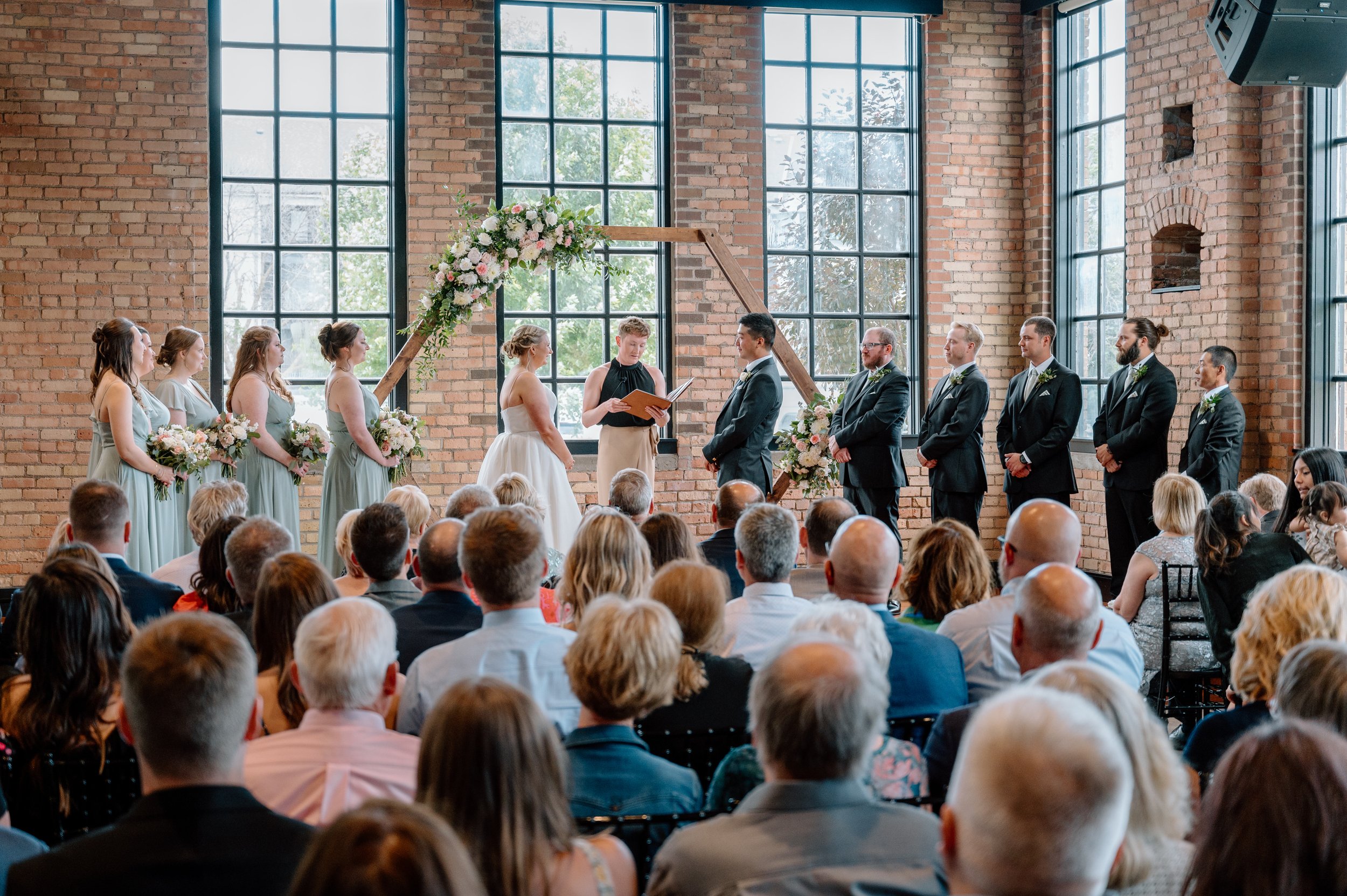 Indoor wedding ceremony with wooden hexagon arch decorated with white and light pink flowers