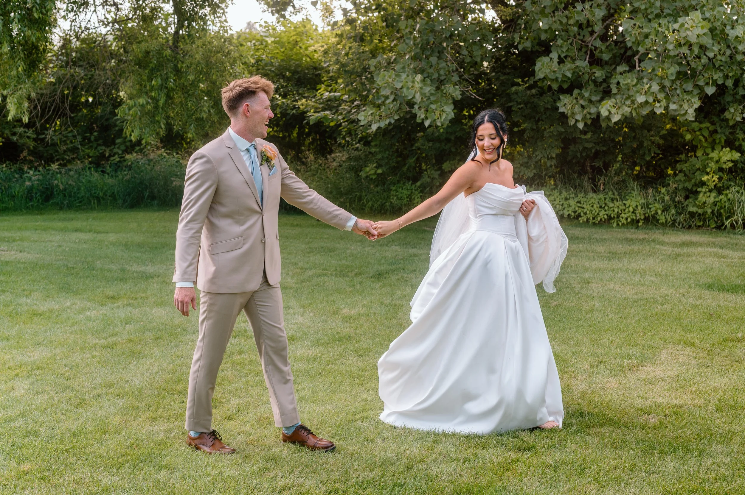 Couple holds hands and walks together while laughing on their wedding day at Gathered Oaks in Alexandria, MN