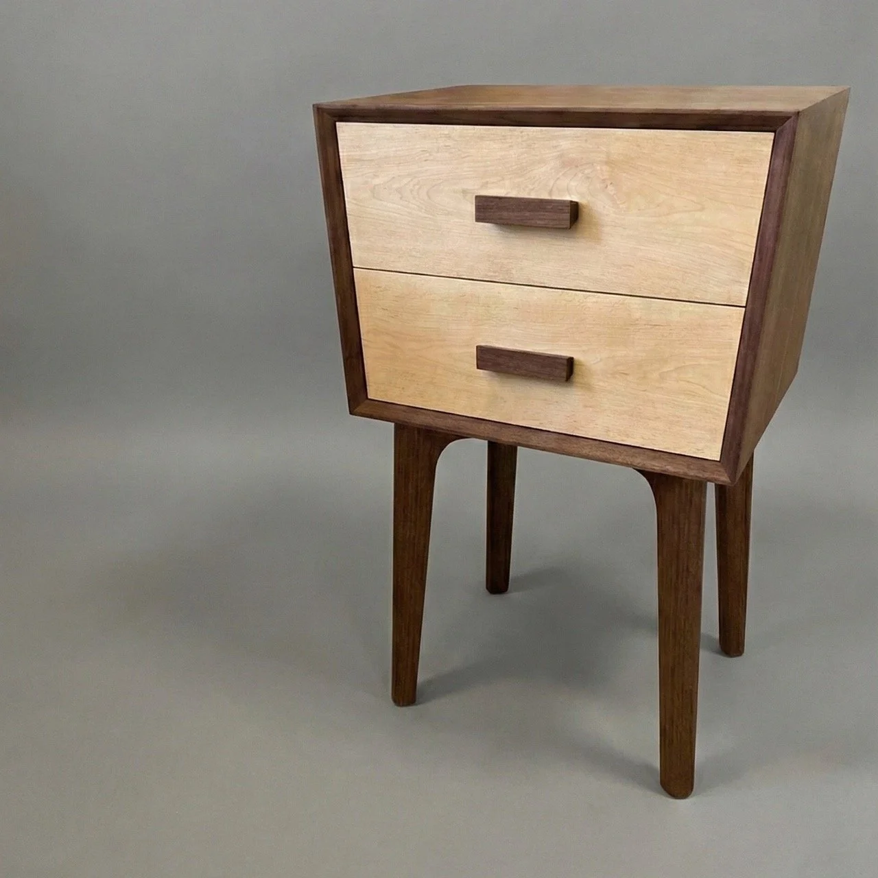 Trapezoid nightstand made of walnut with two drawers made of maple