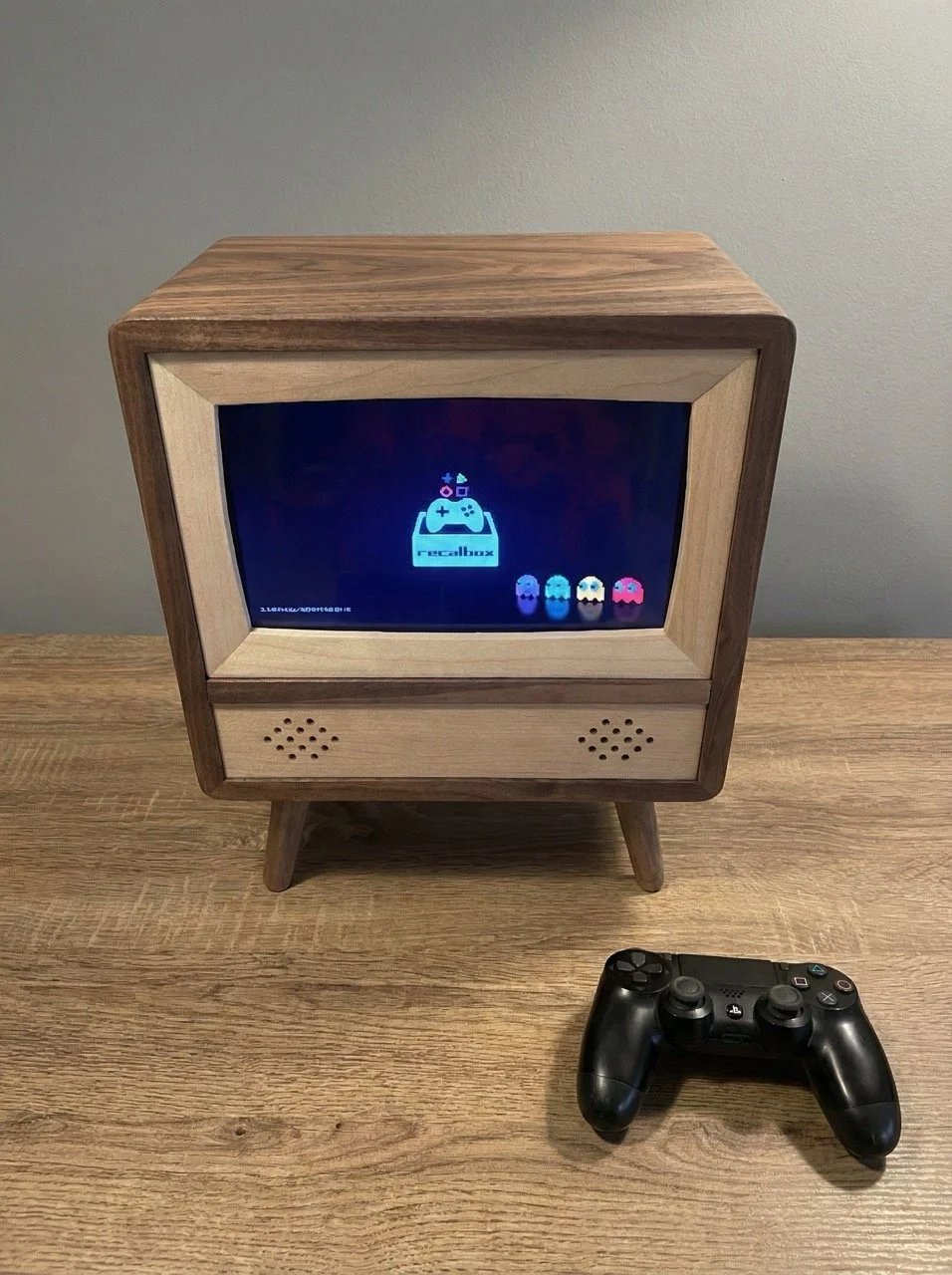 A retro-style TV made of walnut and maple with a video game on the screen and a PS4 controller on the table