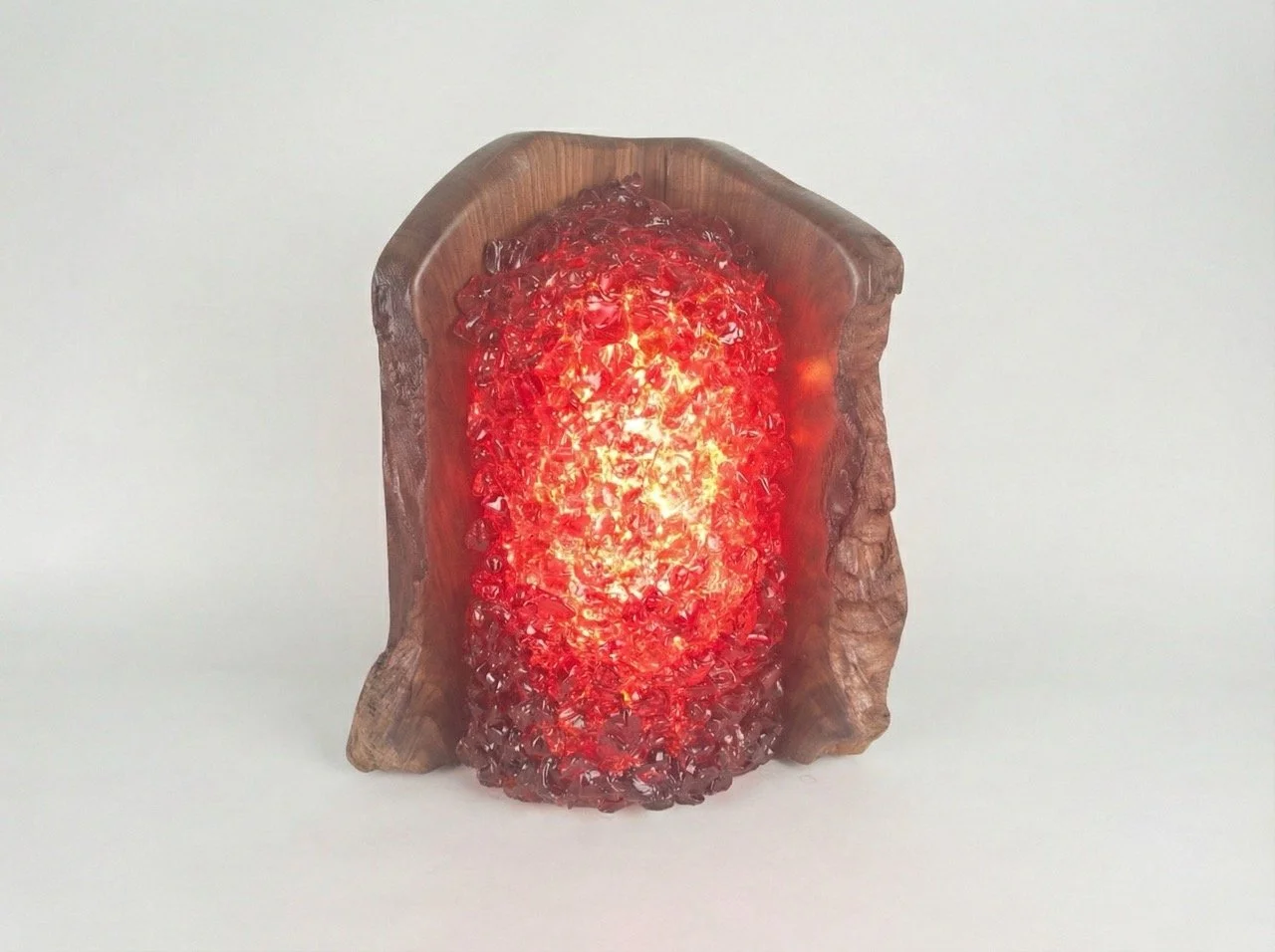 A lamp made of walnut wood with red glass surrounding the bulb
