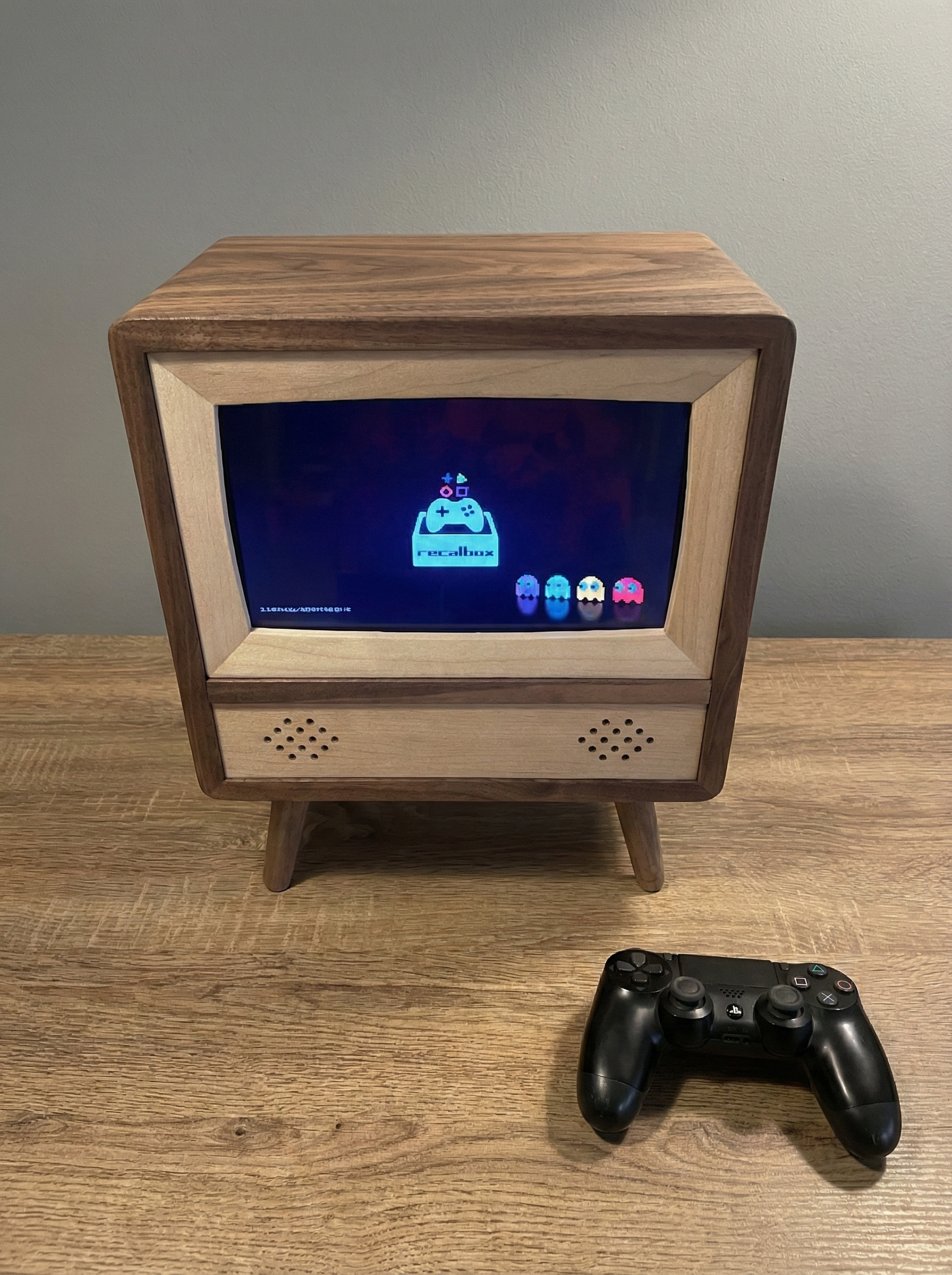 A retro-style TV made of walnut and maple with a video game on the screen and a PS4 controller on the table