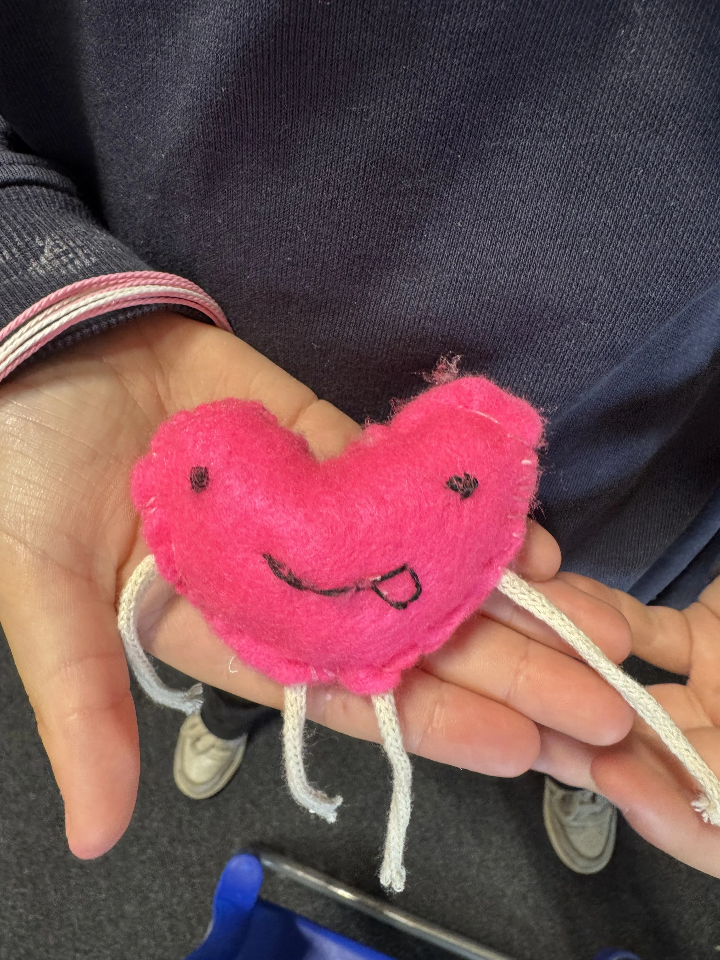 handmade felt heart character with a smiley face that has been hand sewn by one of the pupils