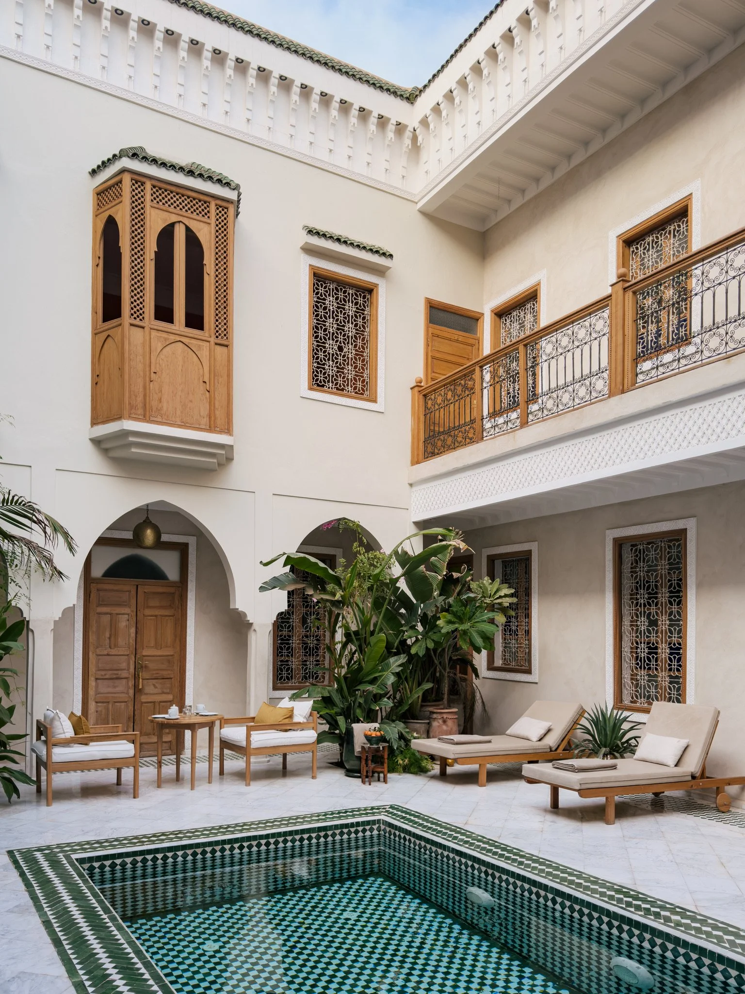 Bathroom with a copper sink, white towel, soap dispenser, soap, and a mirror reflecting colorful windows and a bedroom.