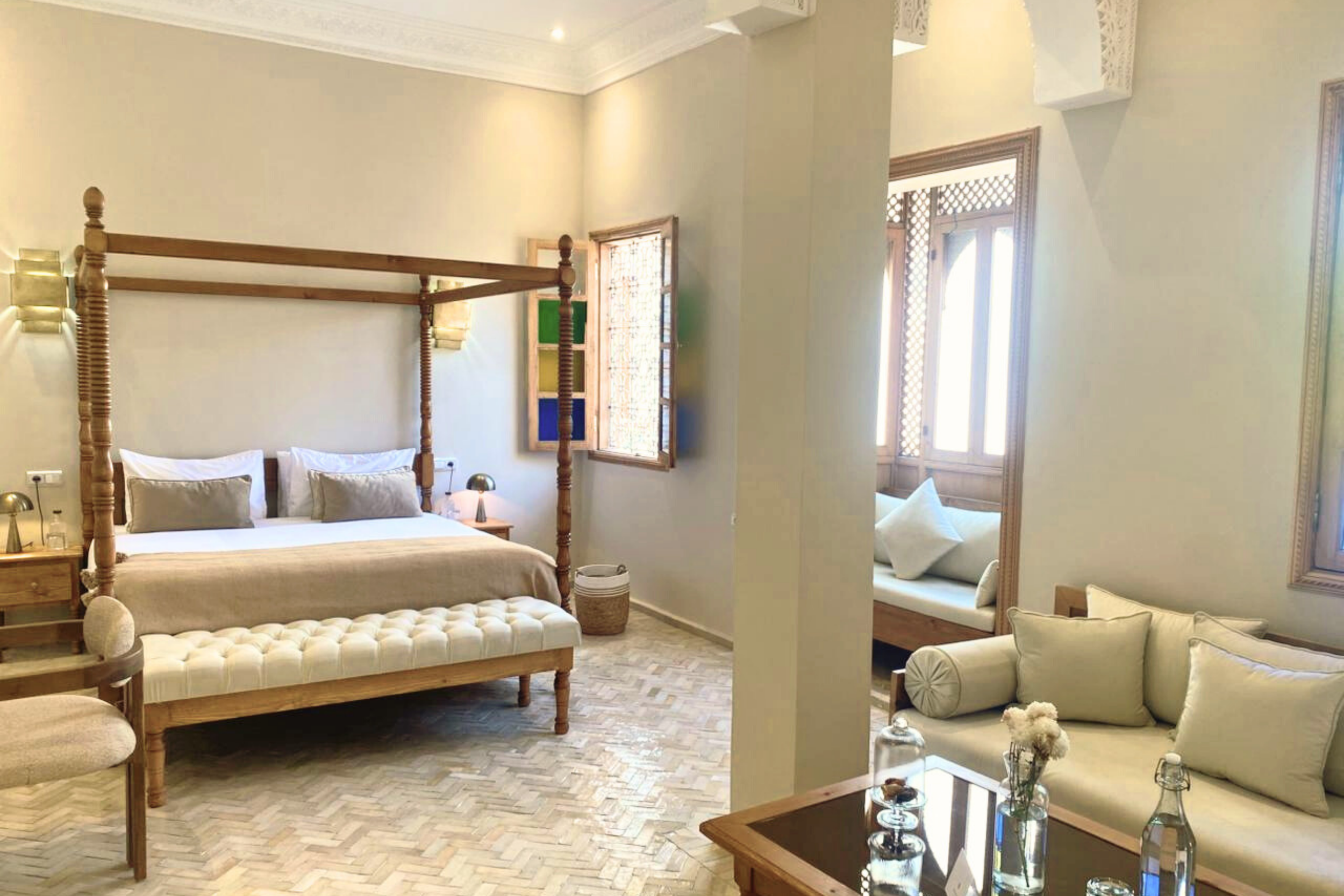 A bedroom in a hotel with a bed, two bedside tables with lamps, and decorative archway and wall details.