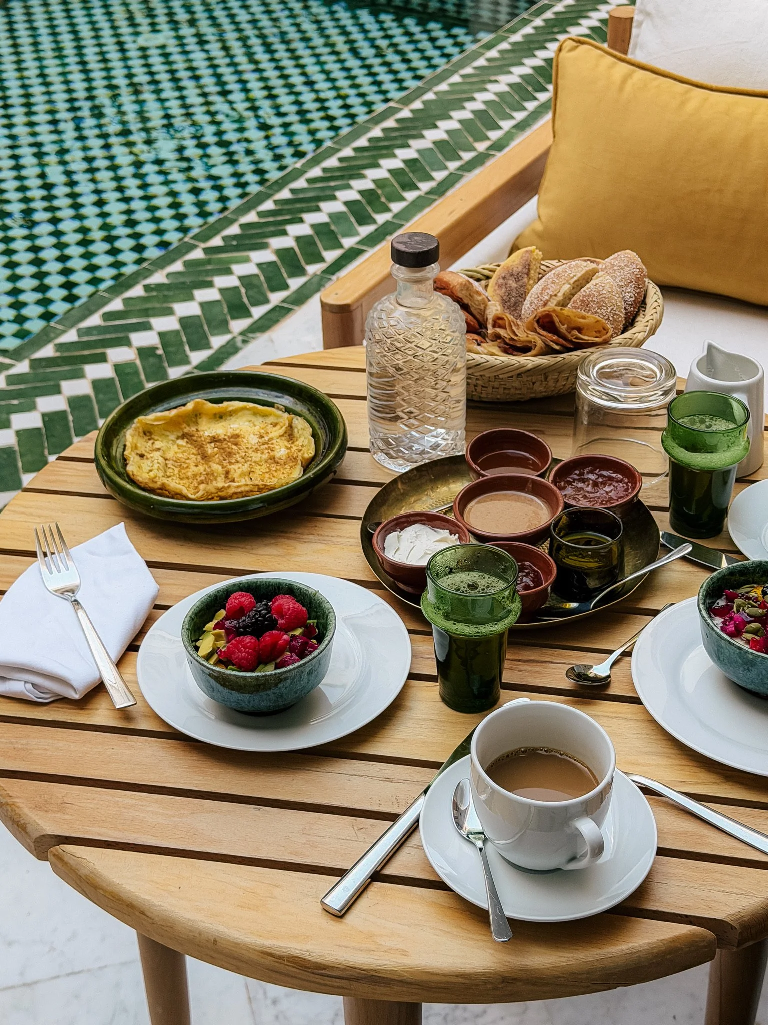 A bedroom with deep red walls and a bed with white and red bedding. There are two gold-colored wall lamps above the head of the bed. A window with colorful stained-glass panes is on the left, and a wooden door frame is partially visible.