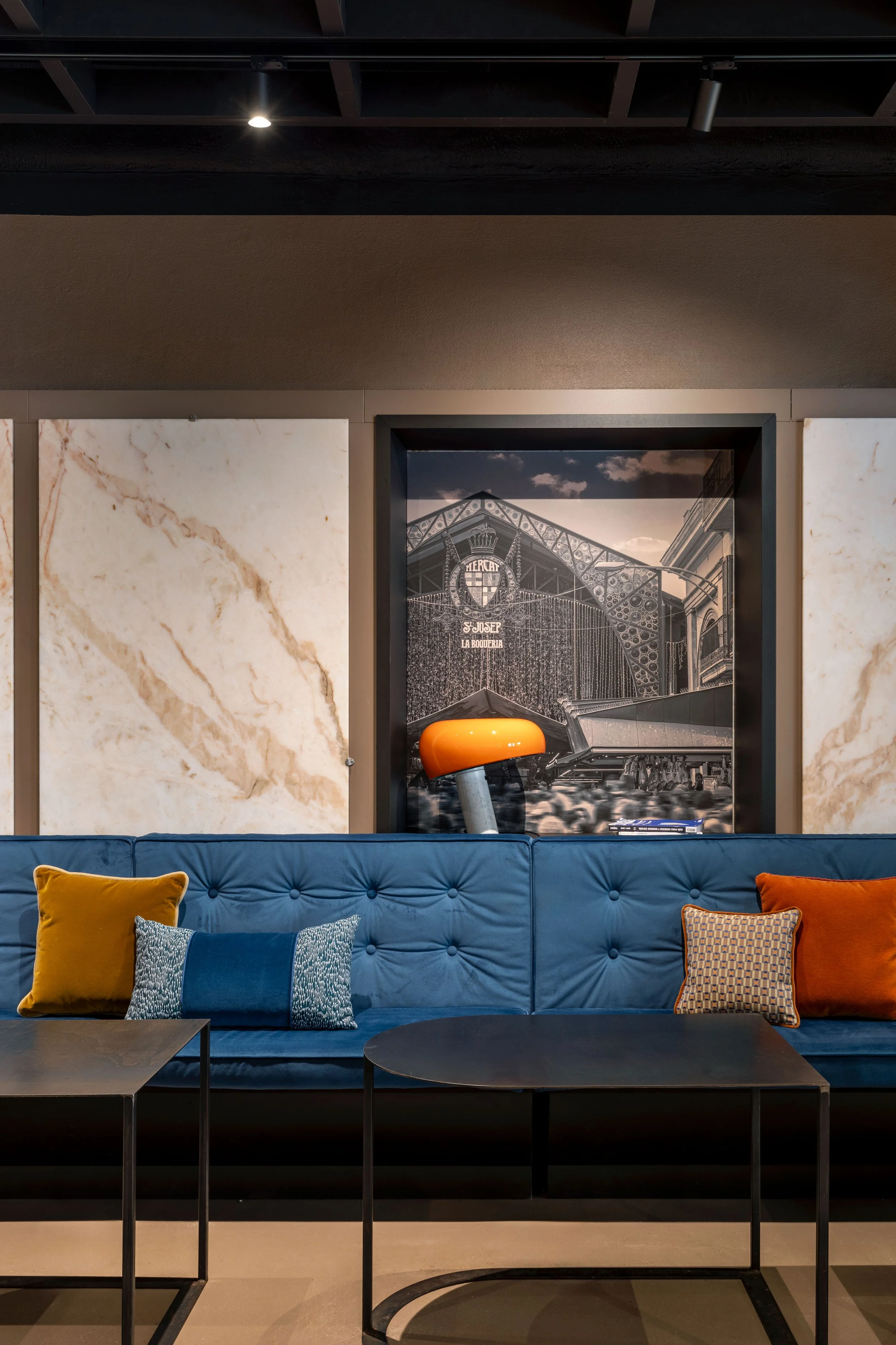 sala ristorante con divano e tavolo conviviale, soffitto nero e pareti e pavimento resinato monocolore, in palette con venature delle vecchie lastre di marmo della macelleria