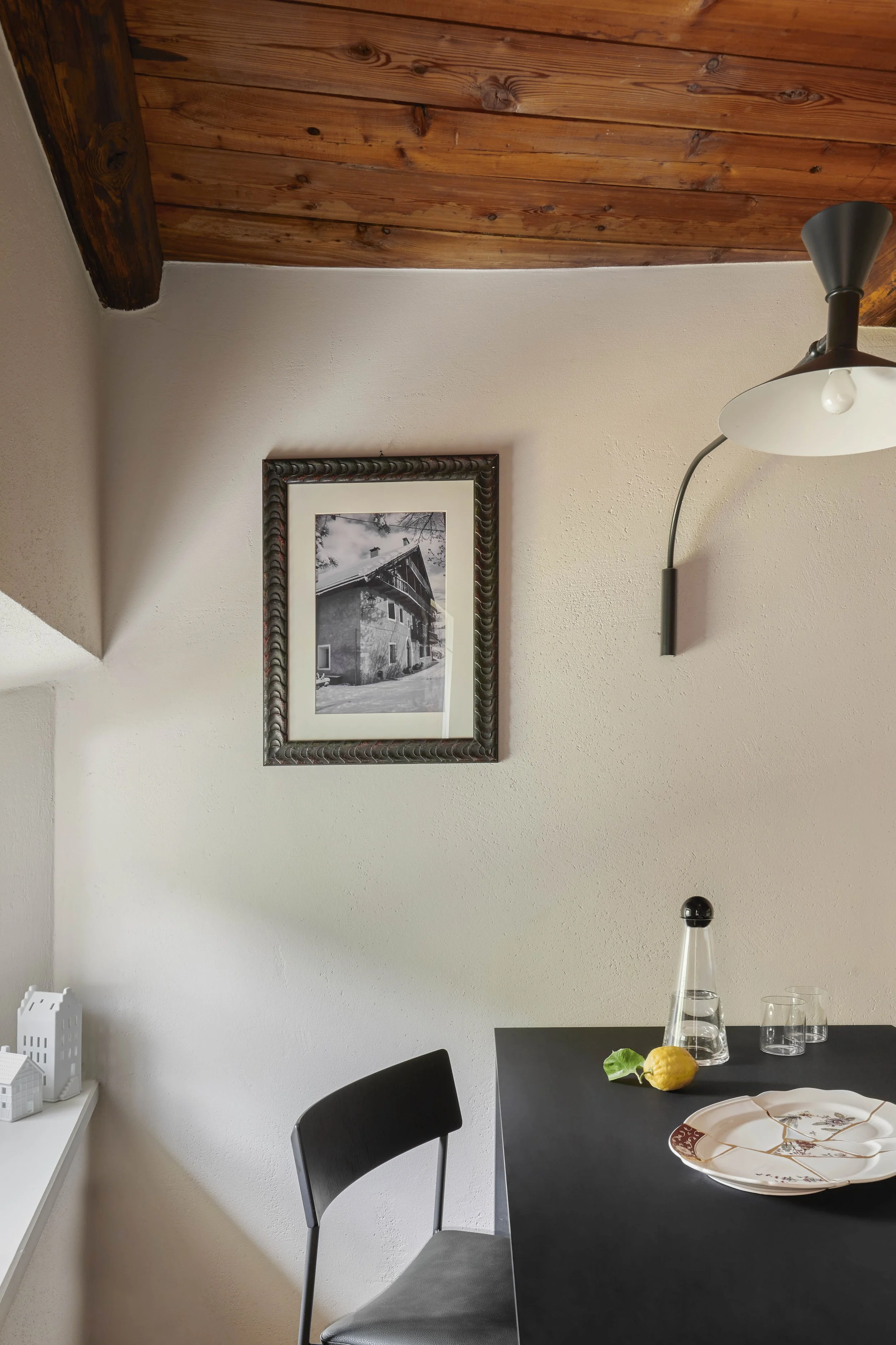 sala da pranzo con tavolo nero in fenix e acciaio, complementi di design e lampada a parete di Le Corbusier.