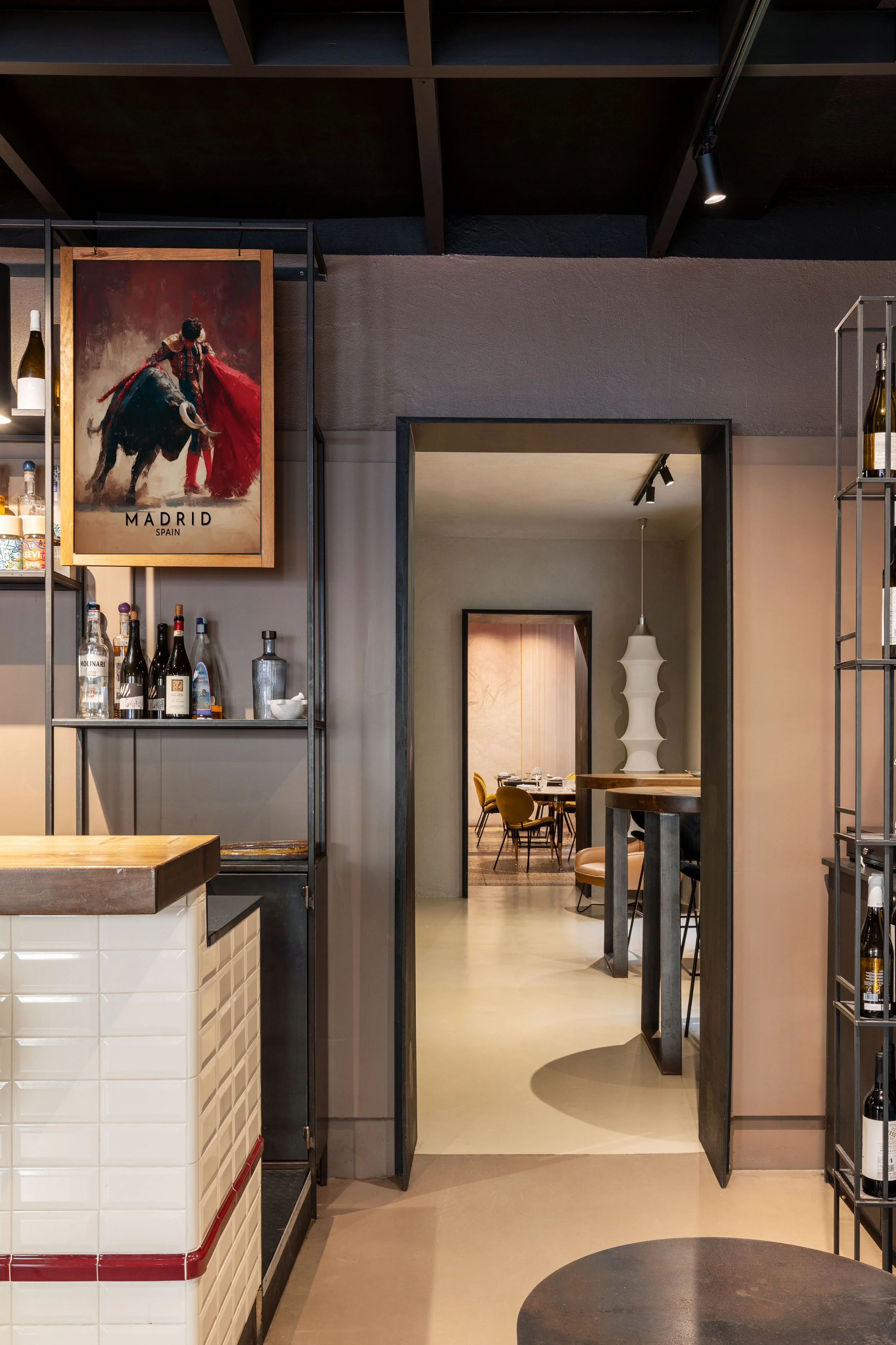accesso al blocco monocolore di collegamento tra le due sale principali, strutture in ferro portabottiglie e tavoli bassi progettate su misura
