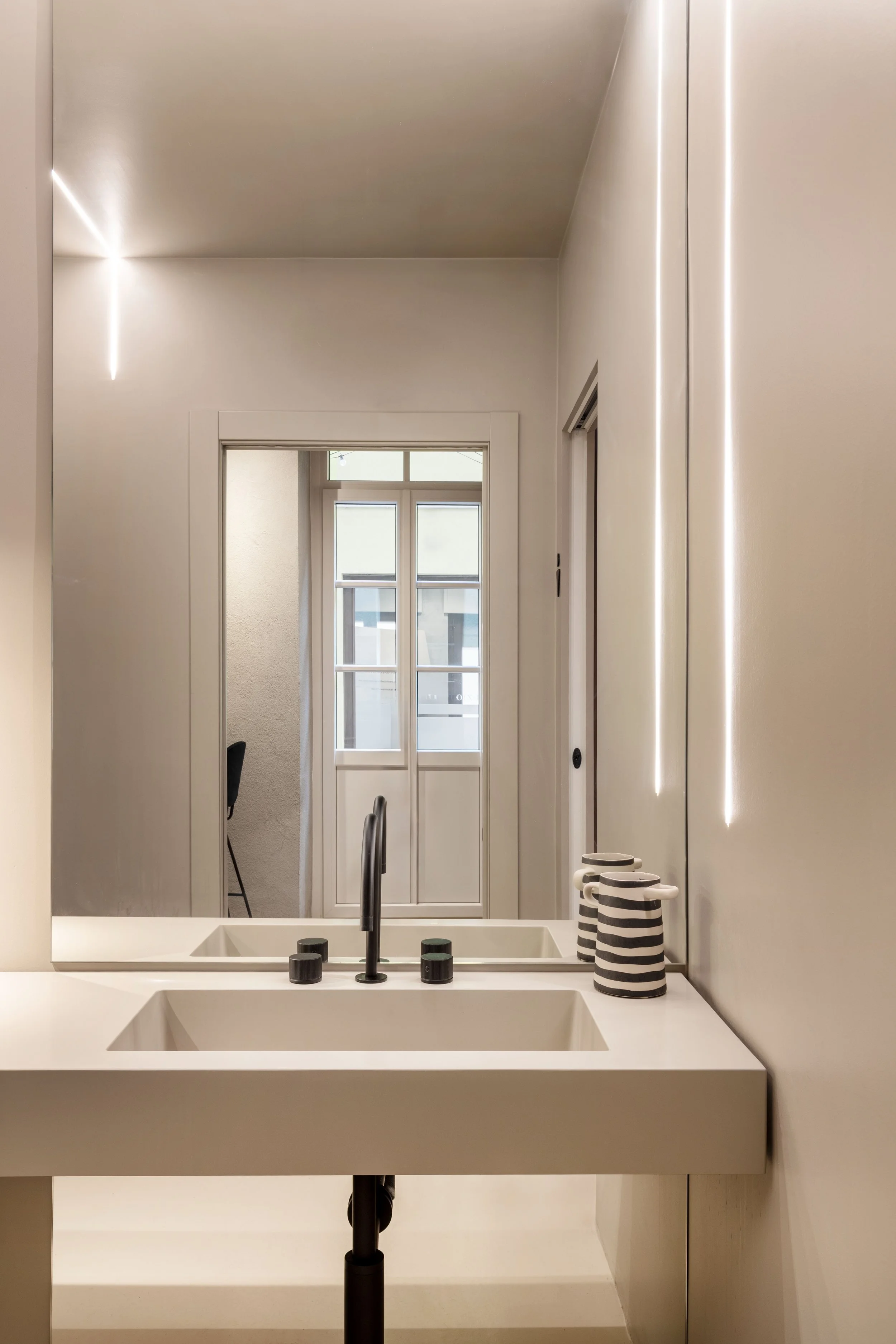 antibagno monocolore sabbia con stripled a incasso e luce puntuale su top, lavabo integrato, rubinetterie e luci nere e specchio tutta altezza
