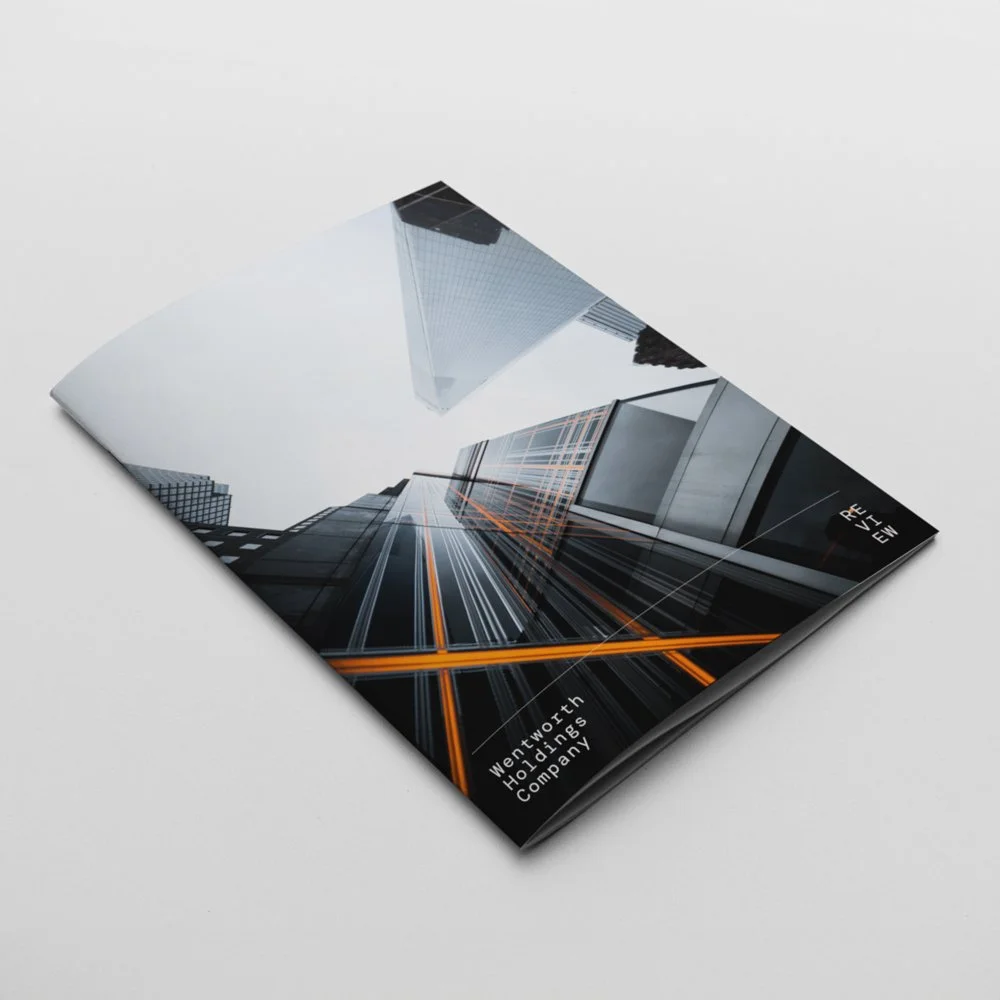 Brochure or magazine with a cover photo of tall modern skyscrapers taken from ground level, showcasing building lights and reflections, with text indicating 'Wentworth Holdings Company' and 'Review'.