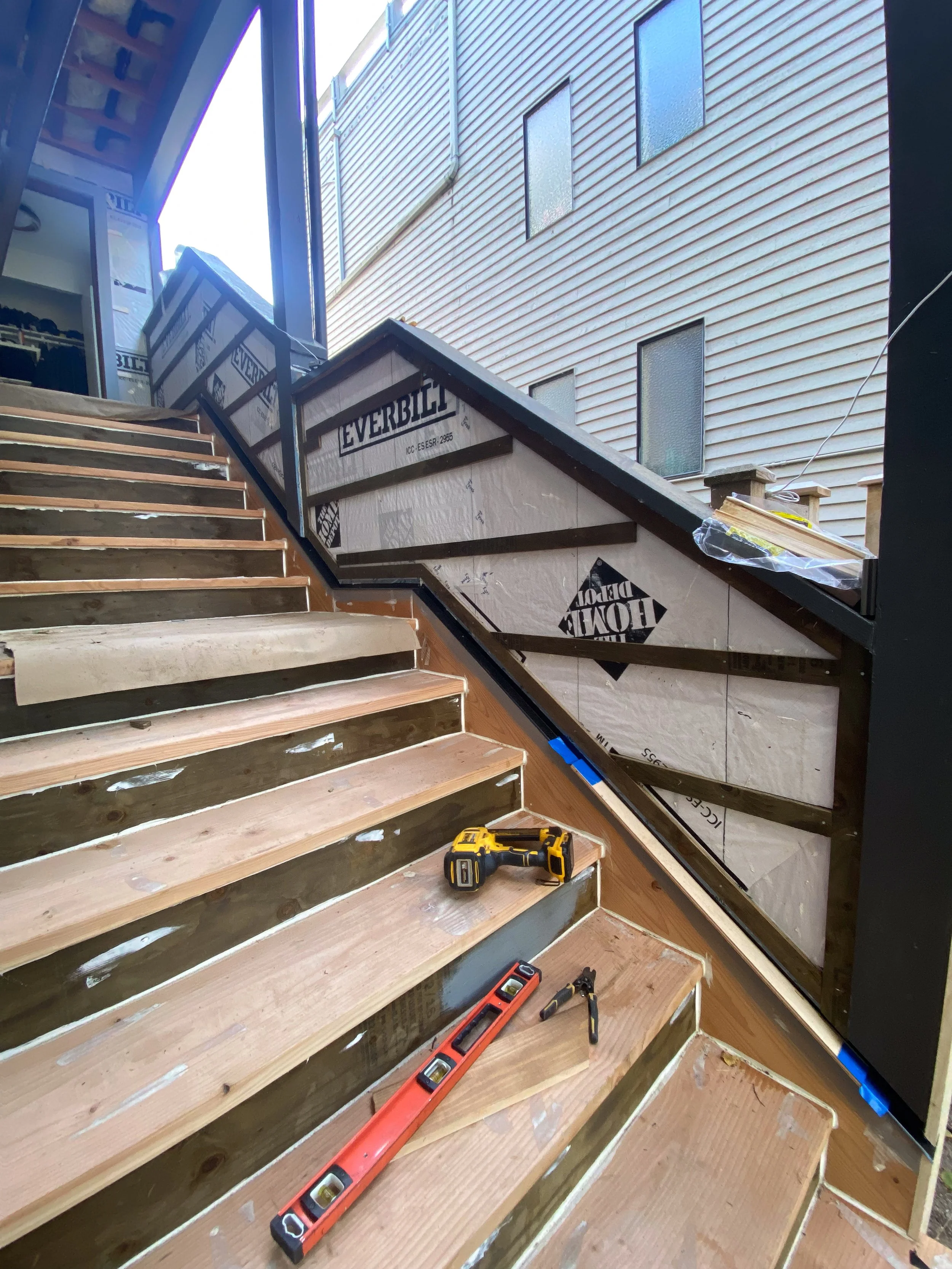 Construction stairs with tools including a drill, level, and measuring tape during building or renovation process.