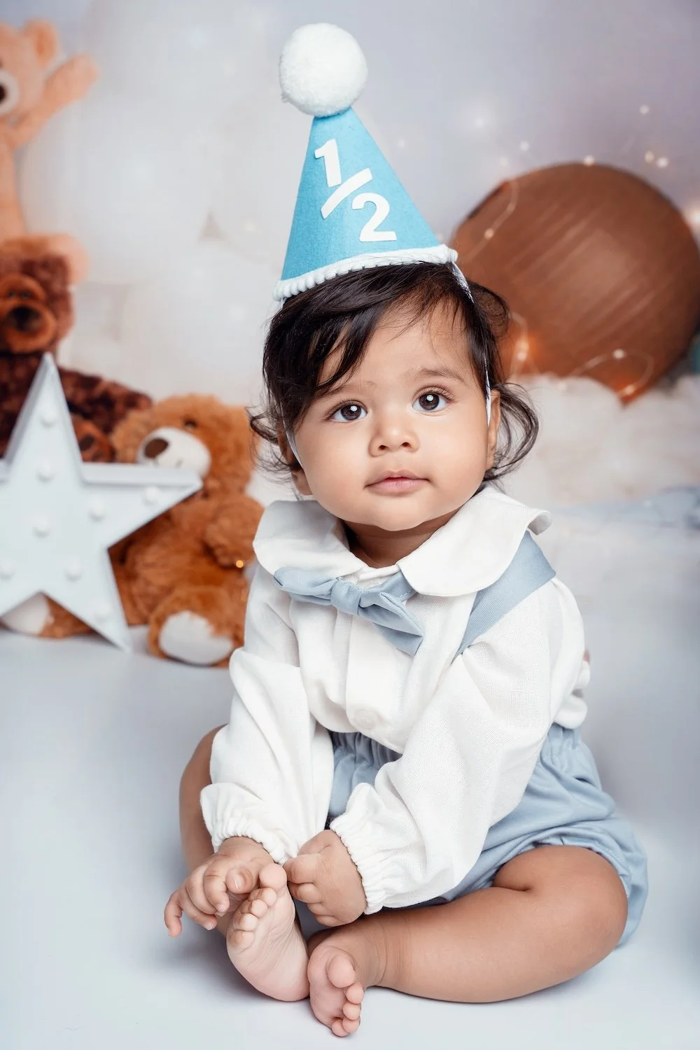  6-month baby boy in a blue "1/2" party hat and bow tie, sitting solo with a teddy bear and star prop, Filaneyka Photo Studio Chicago 