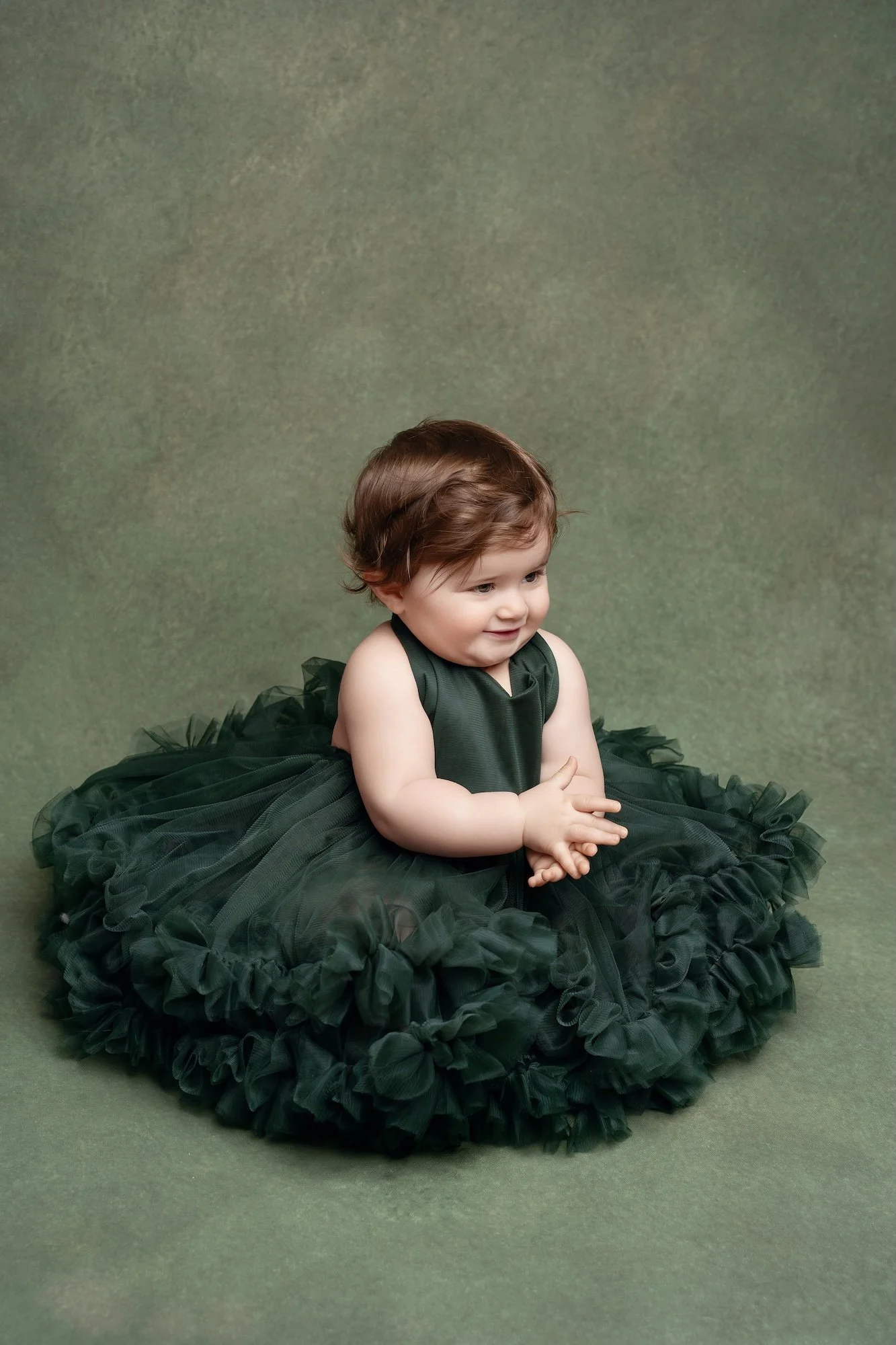  Baby girl in a dark green studio outfit during a first birthday photo session in downtown Chicago 