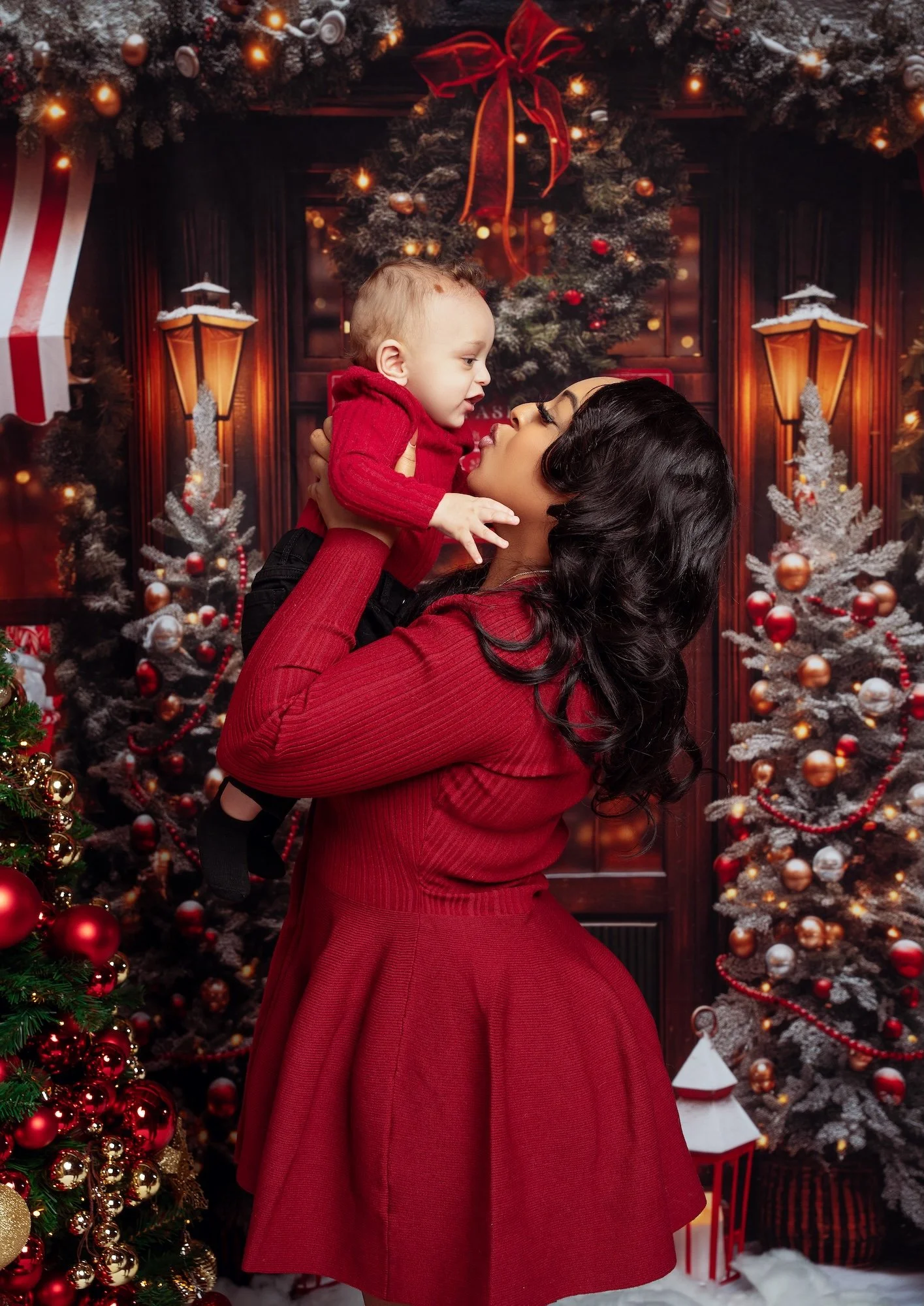  Polished Christmas family portrait in Chicago studio: mother lifting baby in red holiday outfits, professional retouching. 