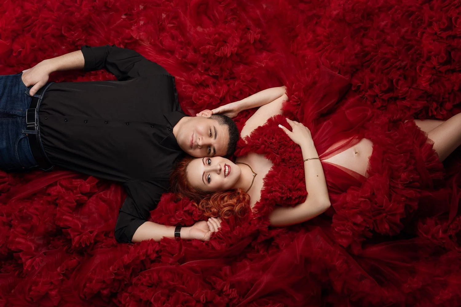 Pregnancy photography with couple lying on red fabric in Chicago - Filaneyka photo studio