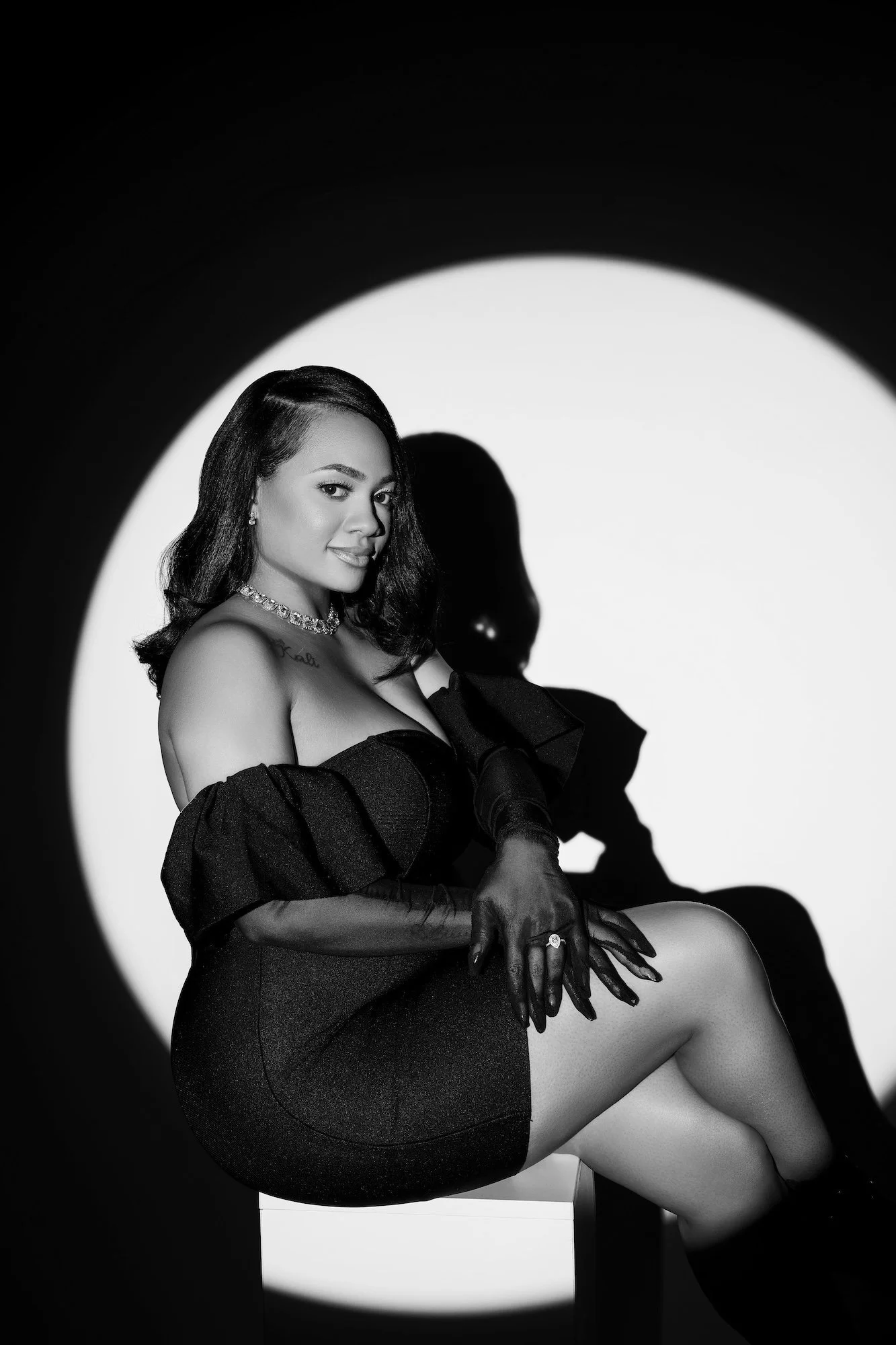 Black and white solo spotlight portrait, engaged woman in black dress with sheer gloves, dramatic circle of light at Filaneyka Photo Studio Chicago