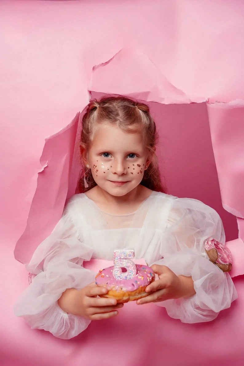 Family photoshoot with girl holding donut on pink backdrop in Chicago - Filaneyka photo studio