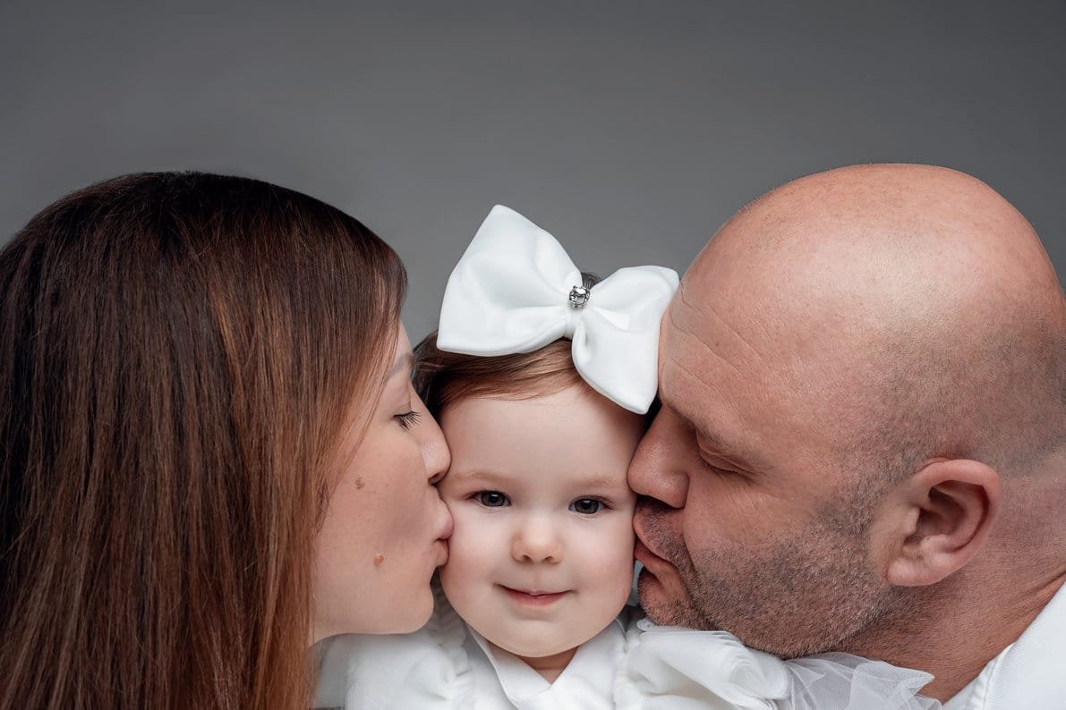 Family photo session with parents kissing daughter cheeks tenderly in Chicago - Filaneyka photo studio