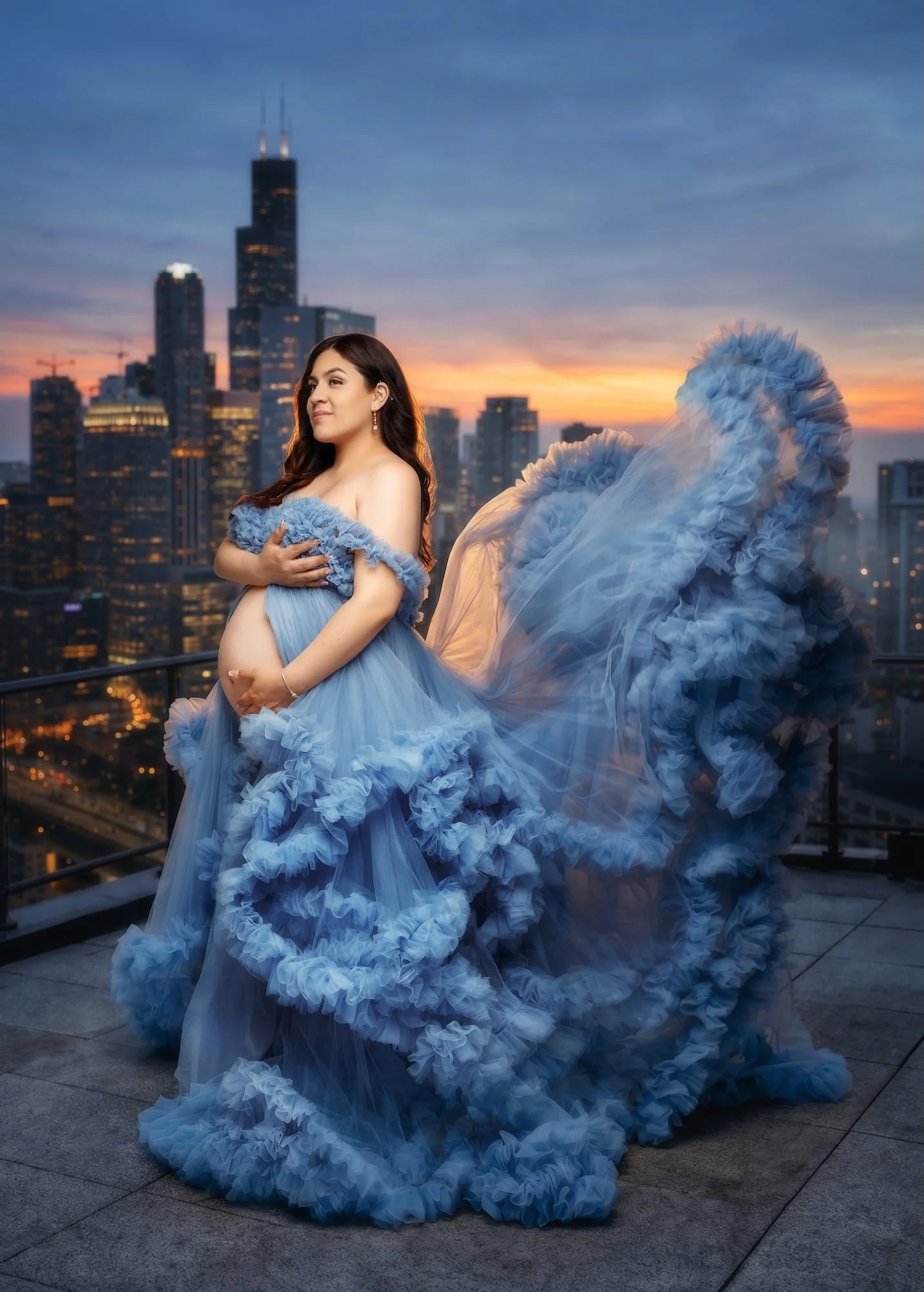 Boutique maternity session: pregnant woman in an elegant blue gown with the Chicago skyline in a soft digital backdrop