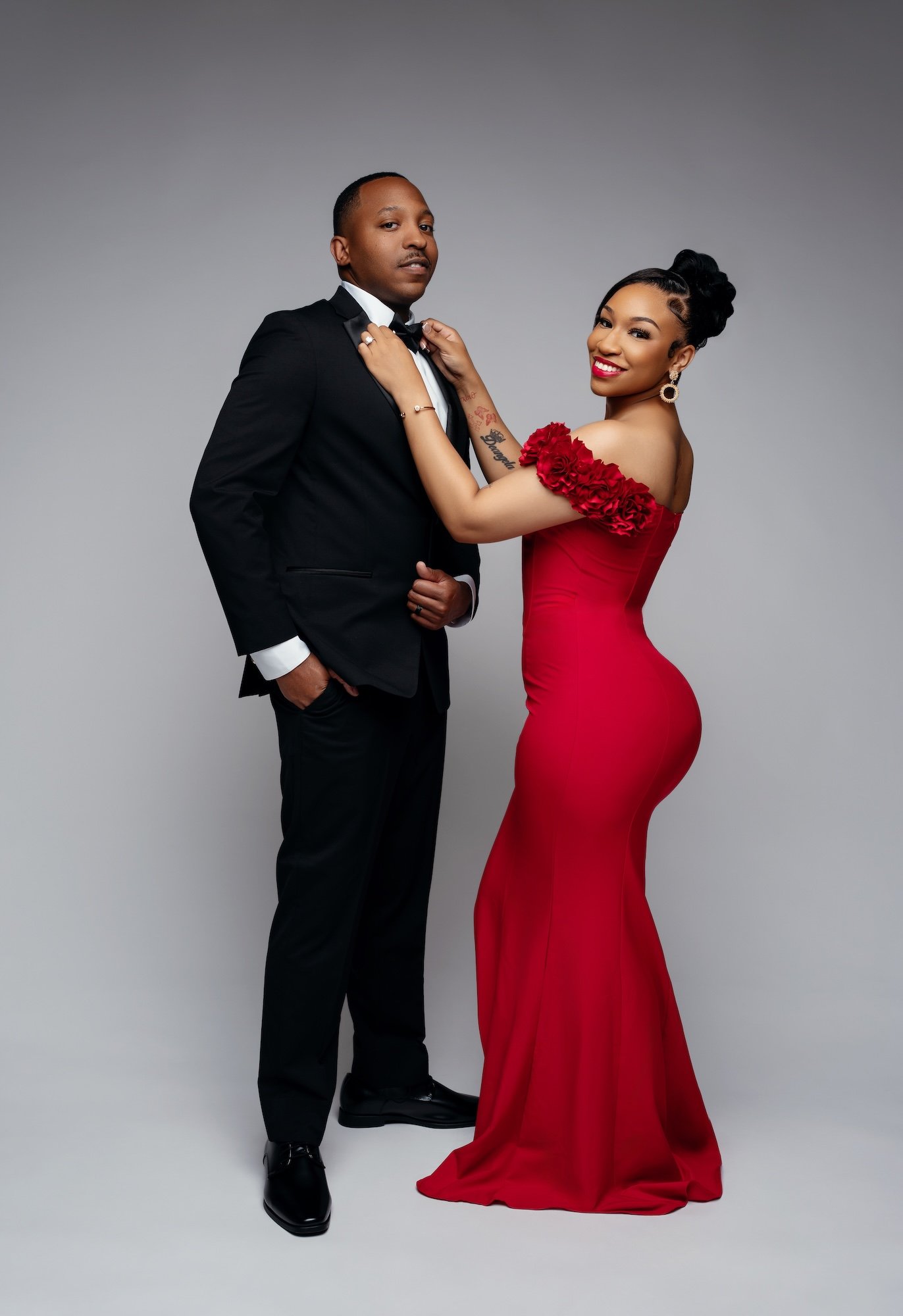 Luxury couple portrait: formal couple with a red gown and tuxedo in the studio