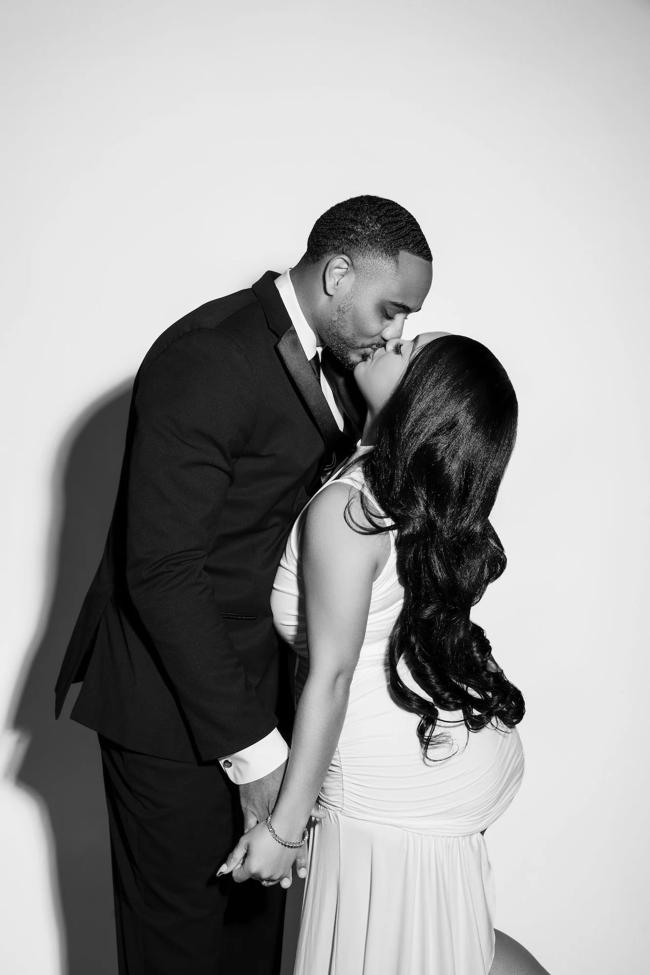 Black and white romantic engagement kiss against white backdrop, dramatic studio portrait at Filaneyka Photo Studio Chicago