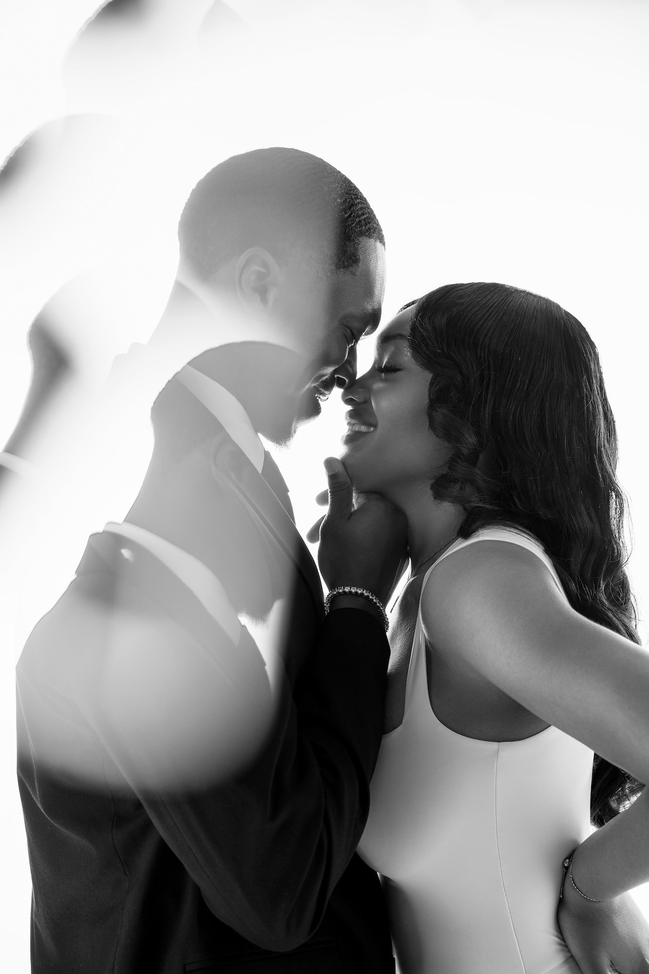 Black and white romantic engagement couple closeup with lens flare, intimate forehead touch in studio portrait at Filaneyka Photo Studio Chicago