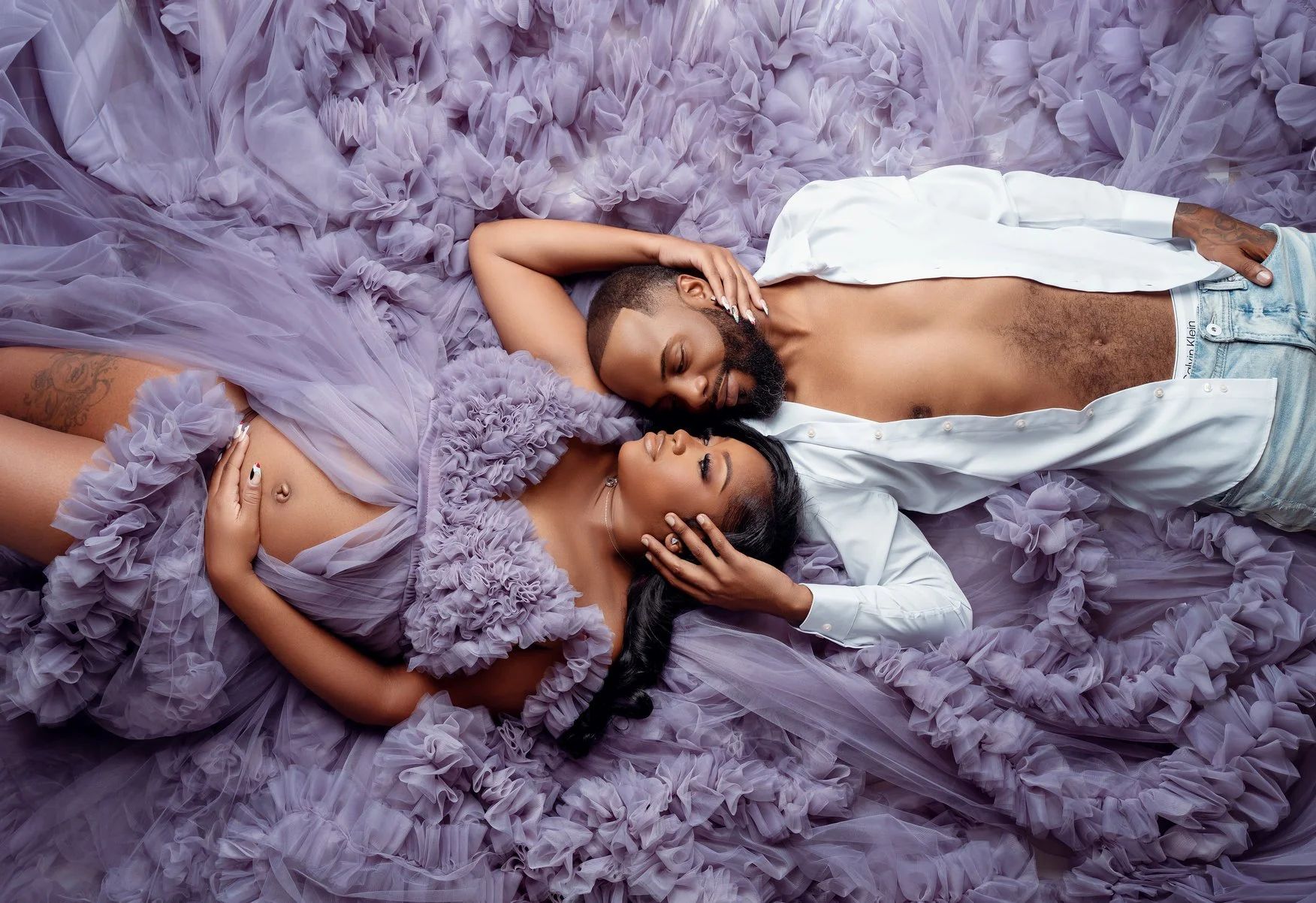 Prenatal photography session with couple lying in purple tulle in Chicago - Filaneyka photo studio