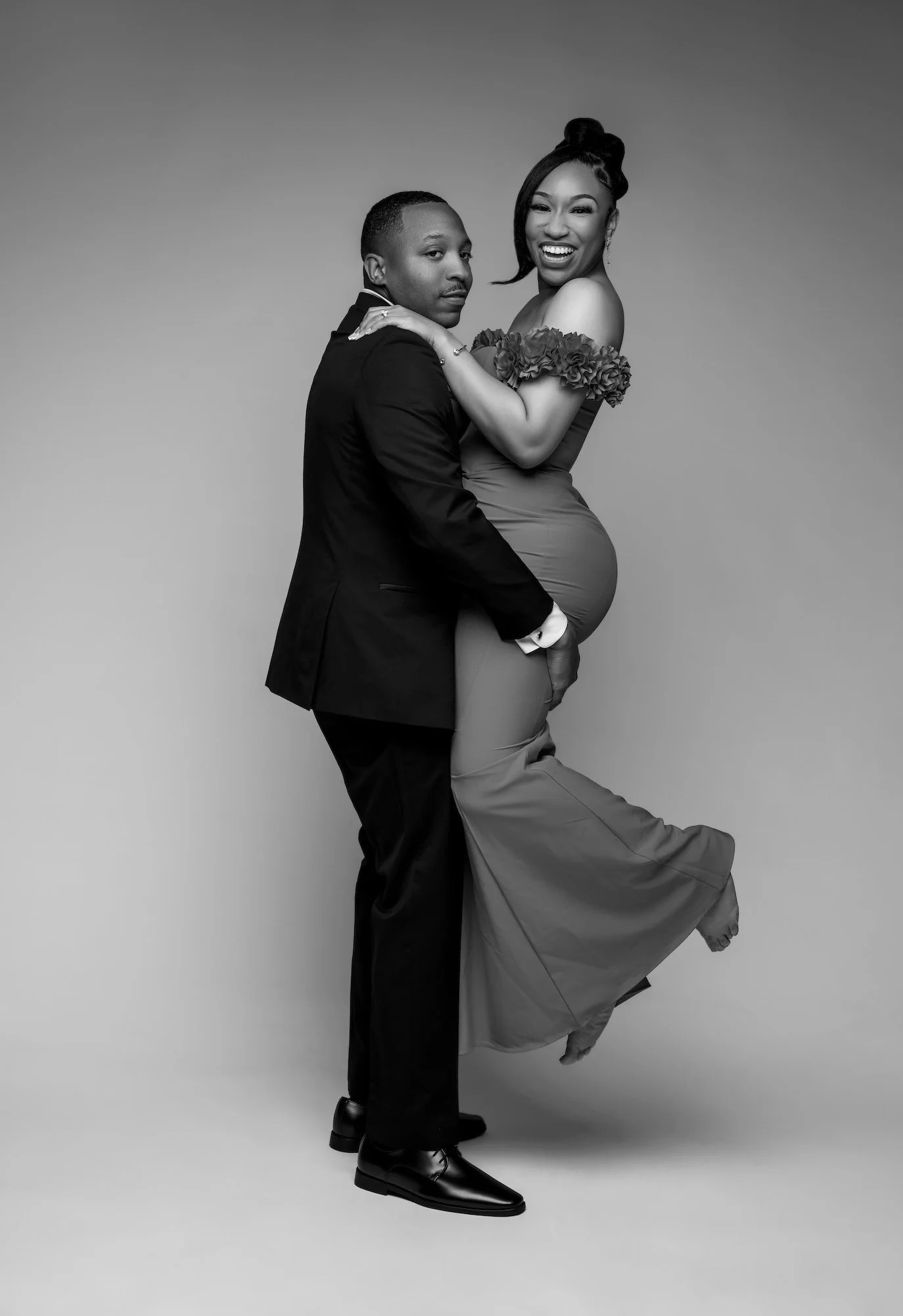 Black and white romantic engagement lift, man carrying laughing woman in red dress, joyful studio photography Chicago
