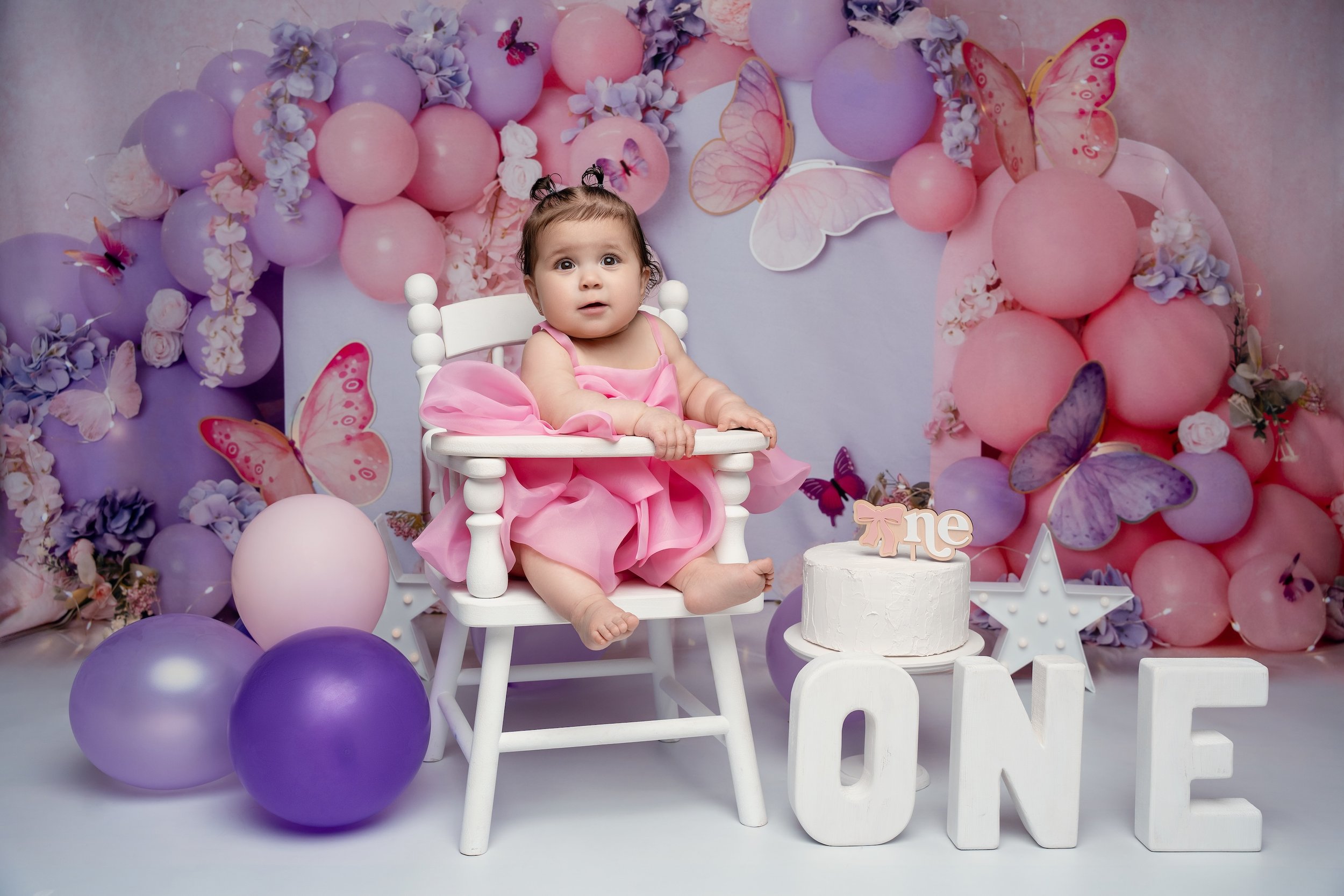 Luxury first birthday session: baby girl in front of a butterfly backdrop