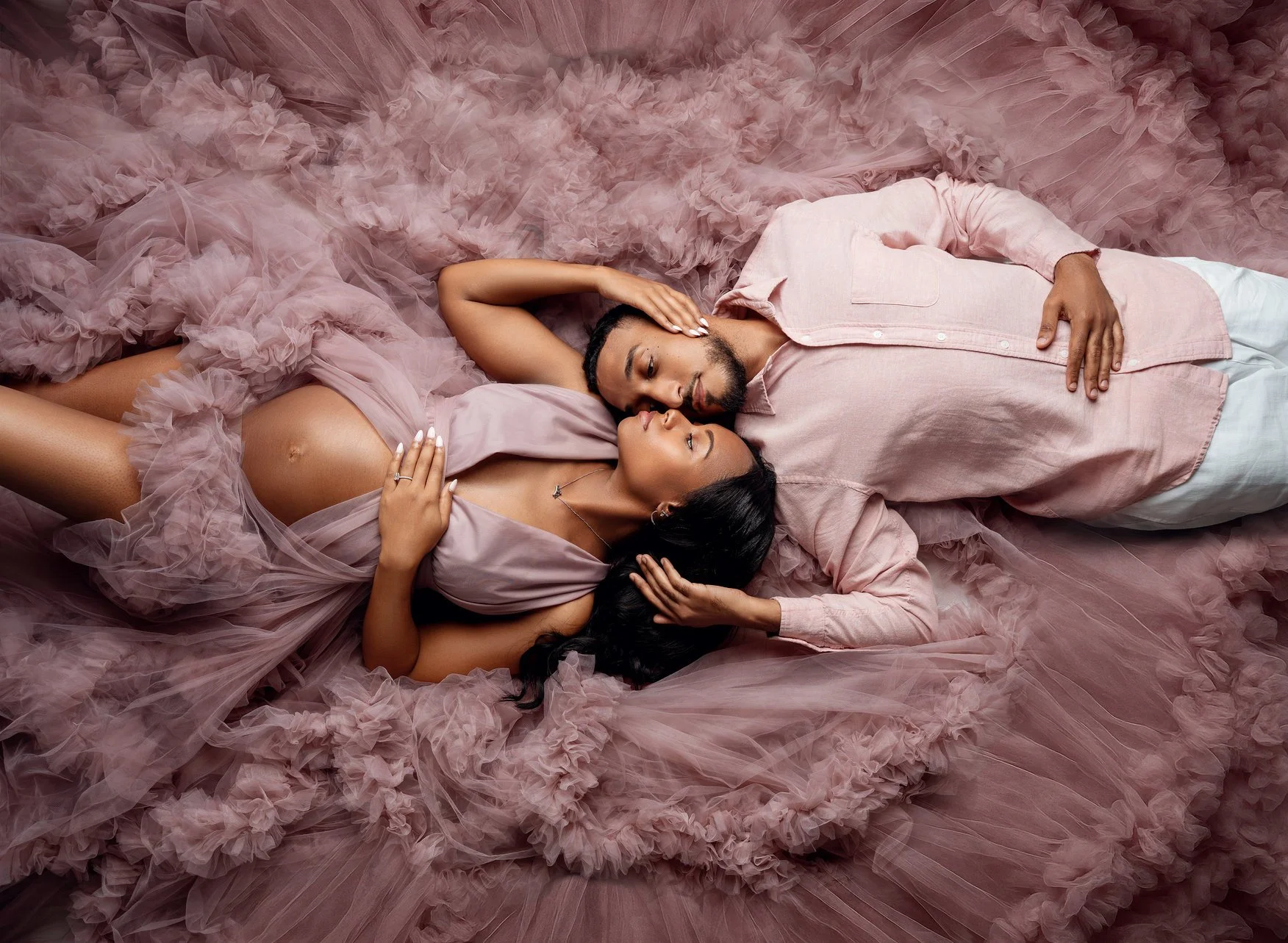 Pregnancy photography with couple lying on pink tulle in Chicago - Filaneyka photo studio