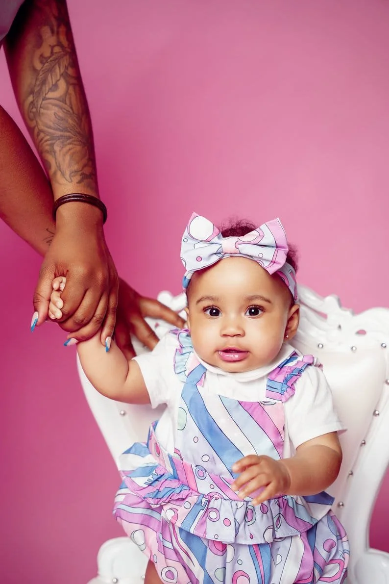Cake smash session with baby holding parent hand on pink backdrop in Chicago - Filaneyka photo studio