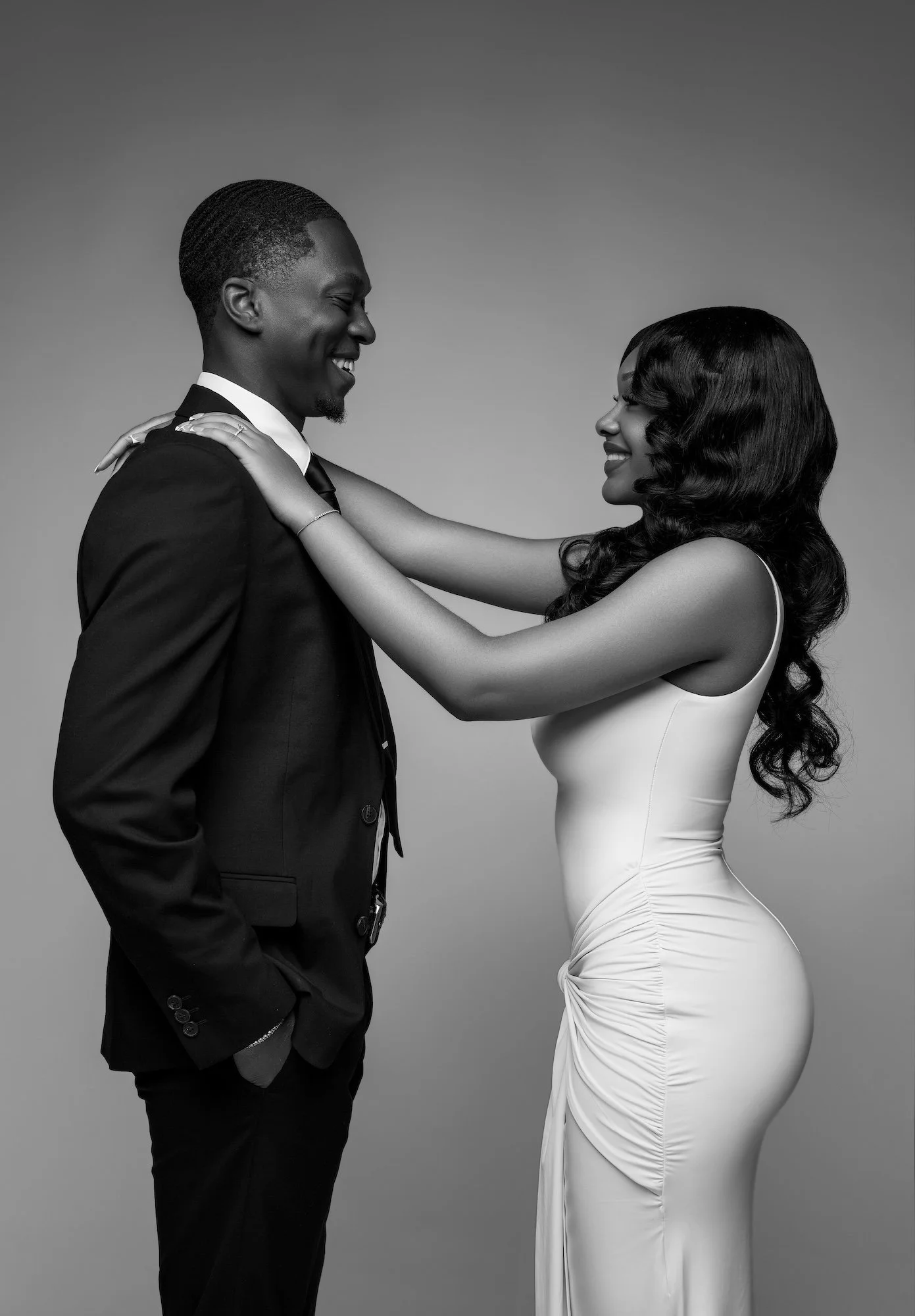 Black and white playful engagement photo, woman adjusting man's collar, candid studio moment at Filaneyka Photo Studio