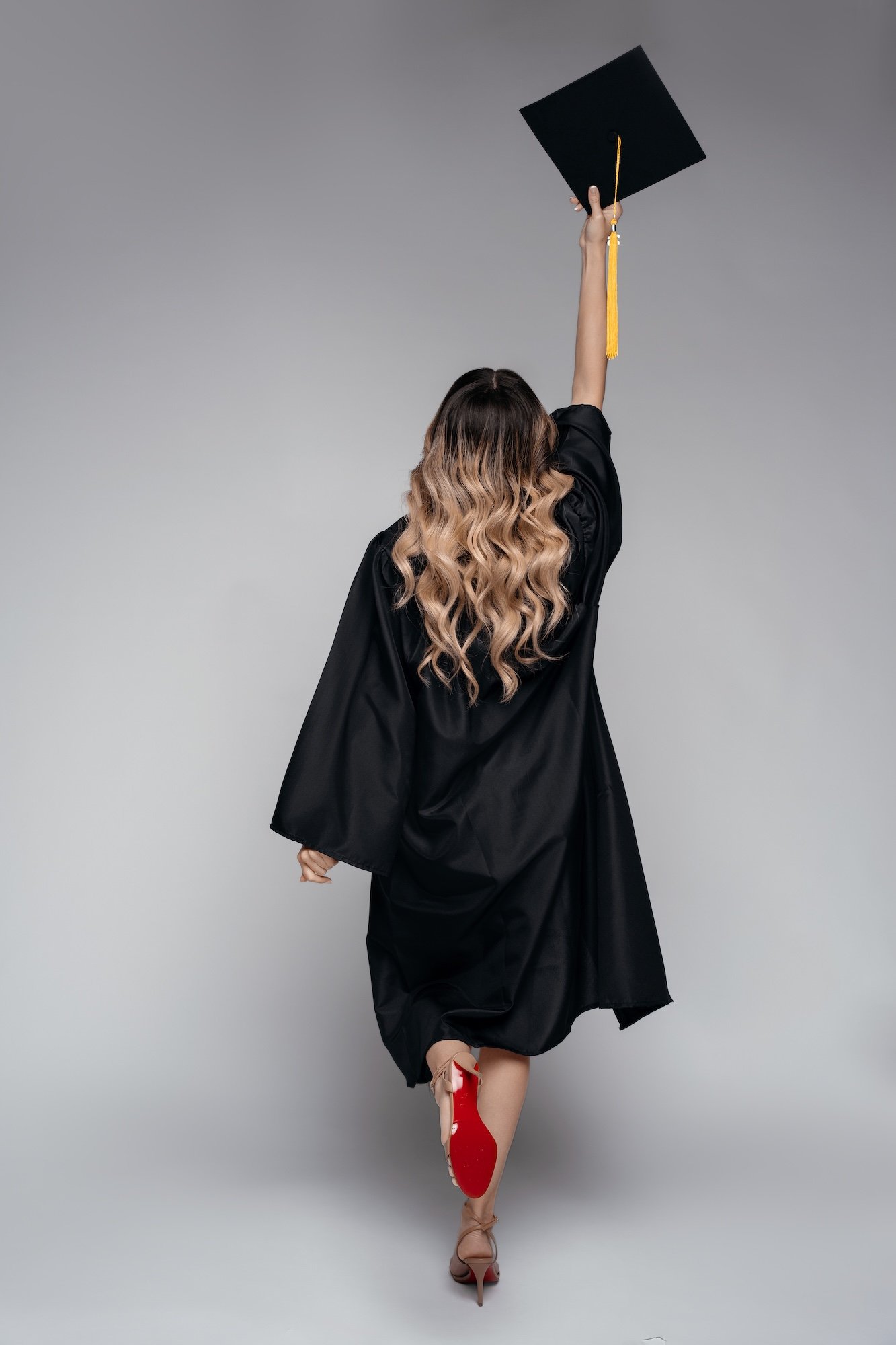 Luxury graduation portrait: woman in cap and gown in the studio