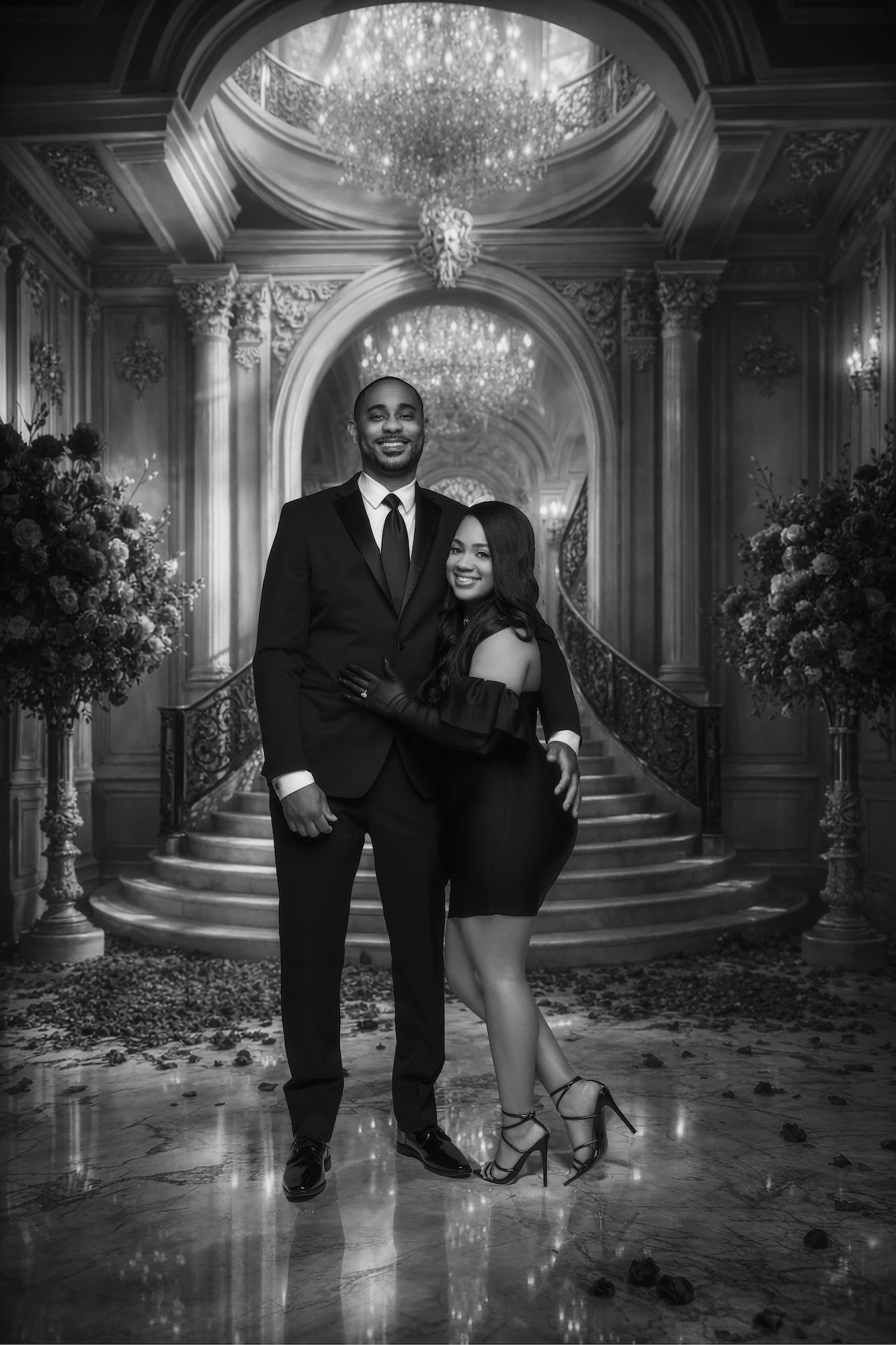 Black and white exclusive retouch engagement photo, couple in ornate grand hall with chandelier, luxury studio portrait at Filaneyka