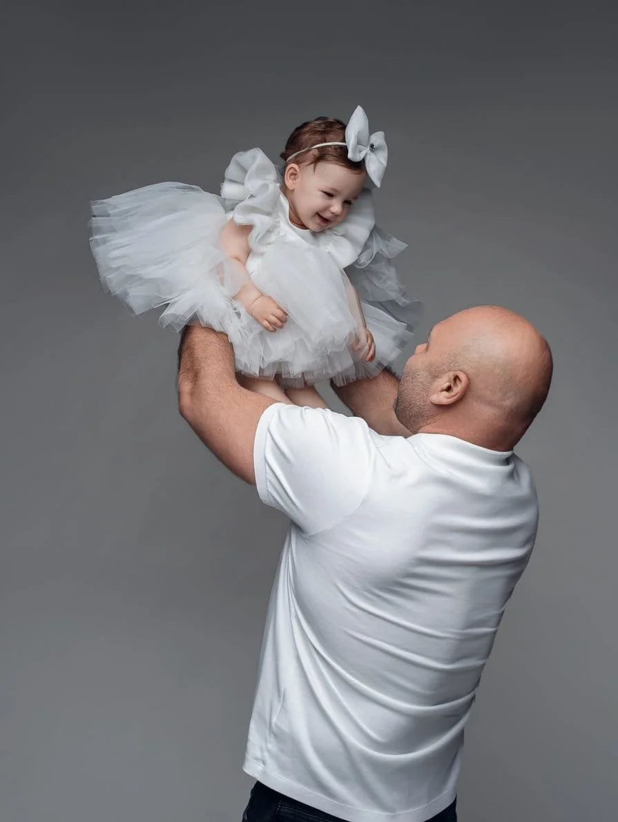 First birthday portrait with father lifting daughter overhead in white tutu in Chicago - Filaneyka photo studio