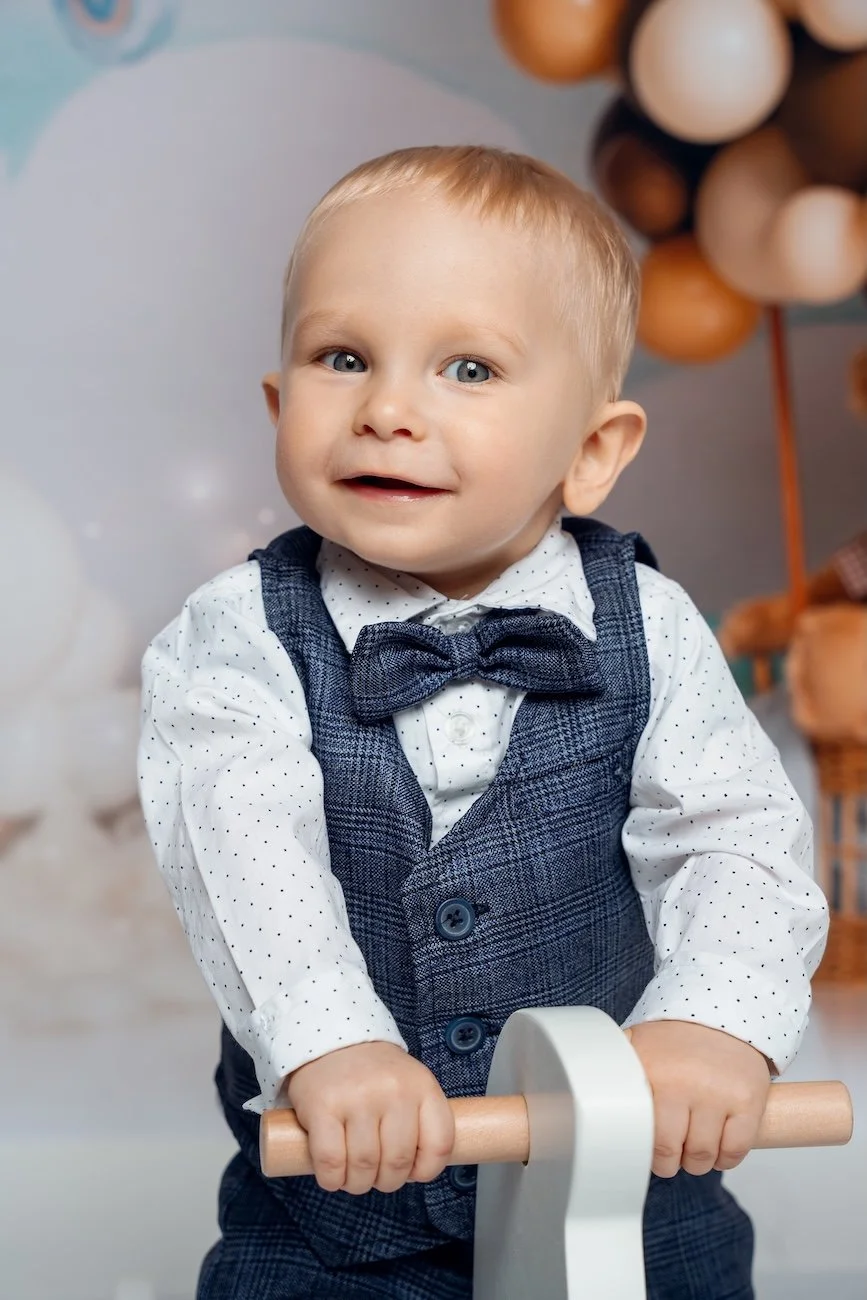 1st birthday photography with toddler boy smiling in bow tie vest in Chicago - Filaneyka photo studio