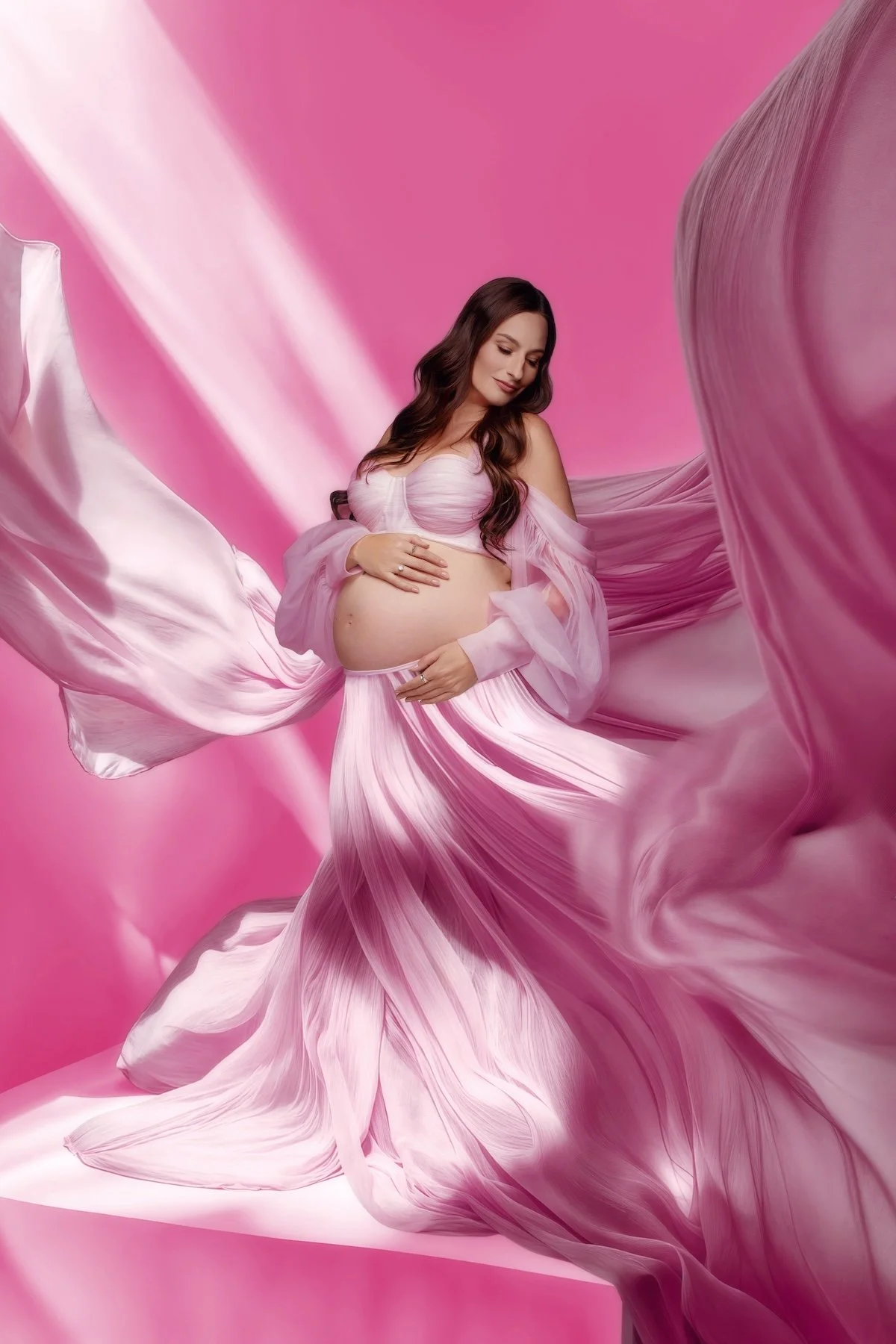 Maternity session with flowing pink fabric drapery and elegant pose on vibrant pink backdrop, Chicago, Filaneyka photo studio