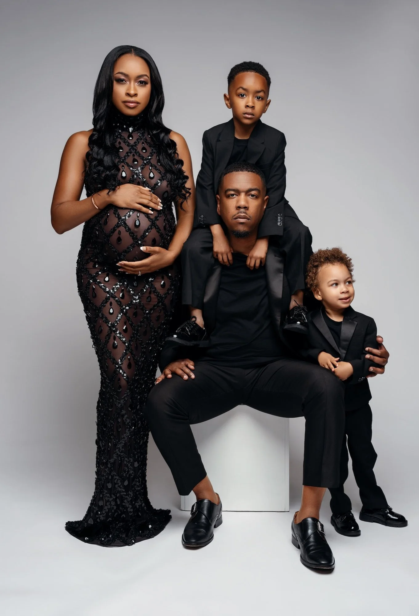 Luxury maternity photoshoot: family session with the woman in a black beaded gown