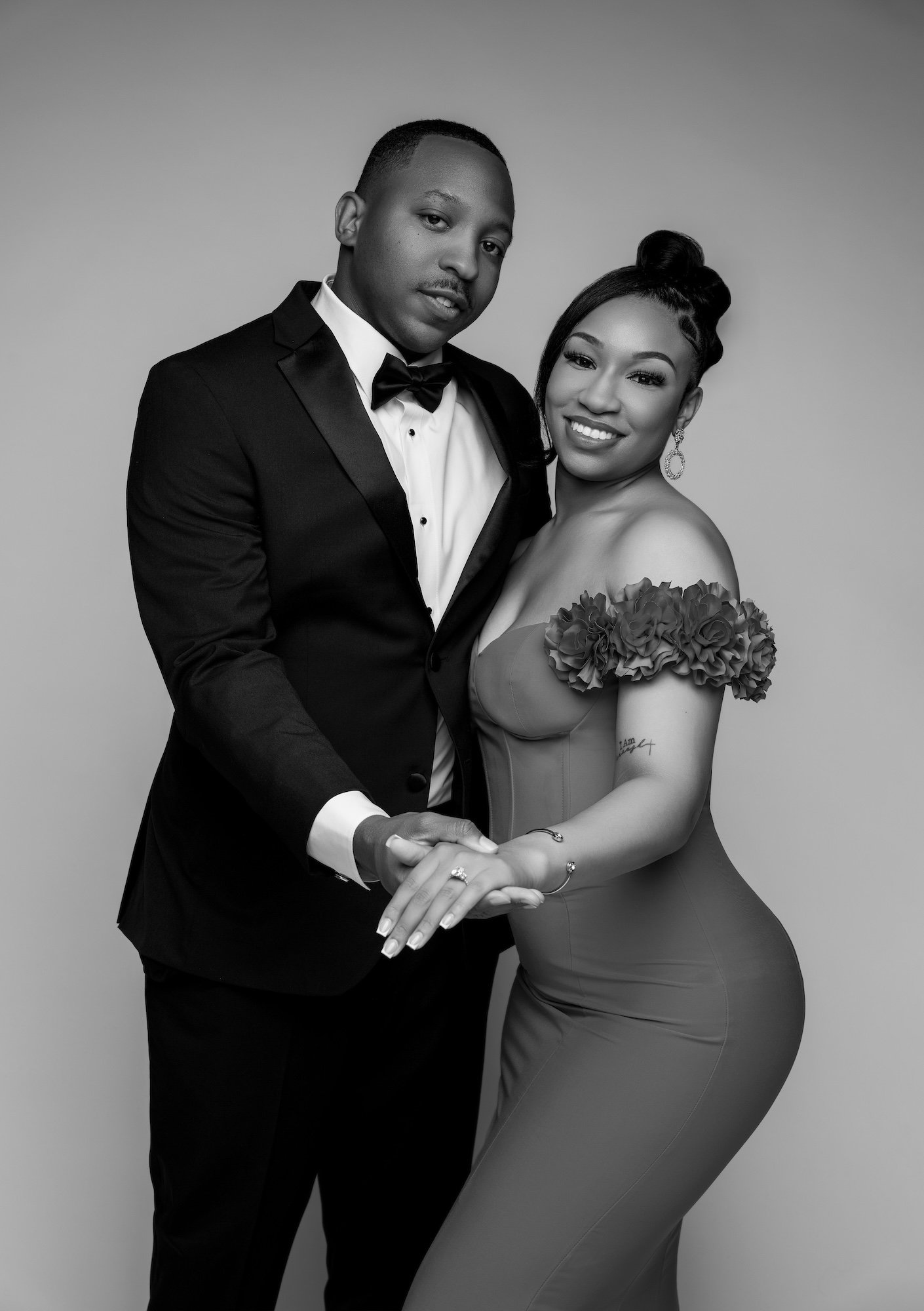Black and white engagement couple holding hands, red dress and tuxedo, intimate studio portrait at Filaneyka Photo Studio