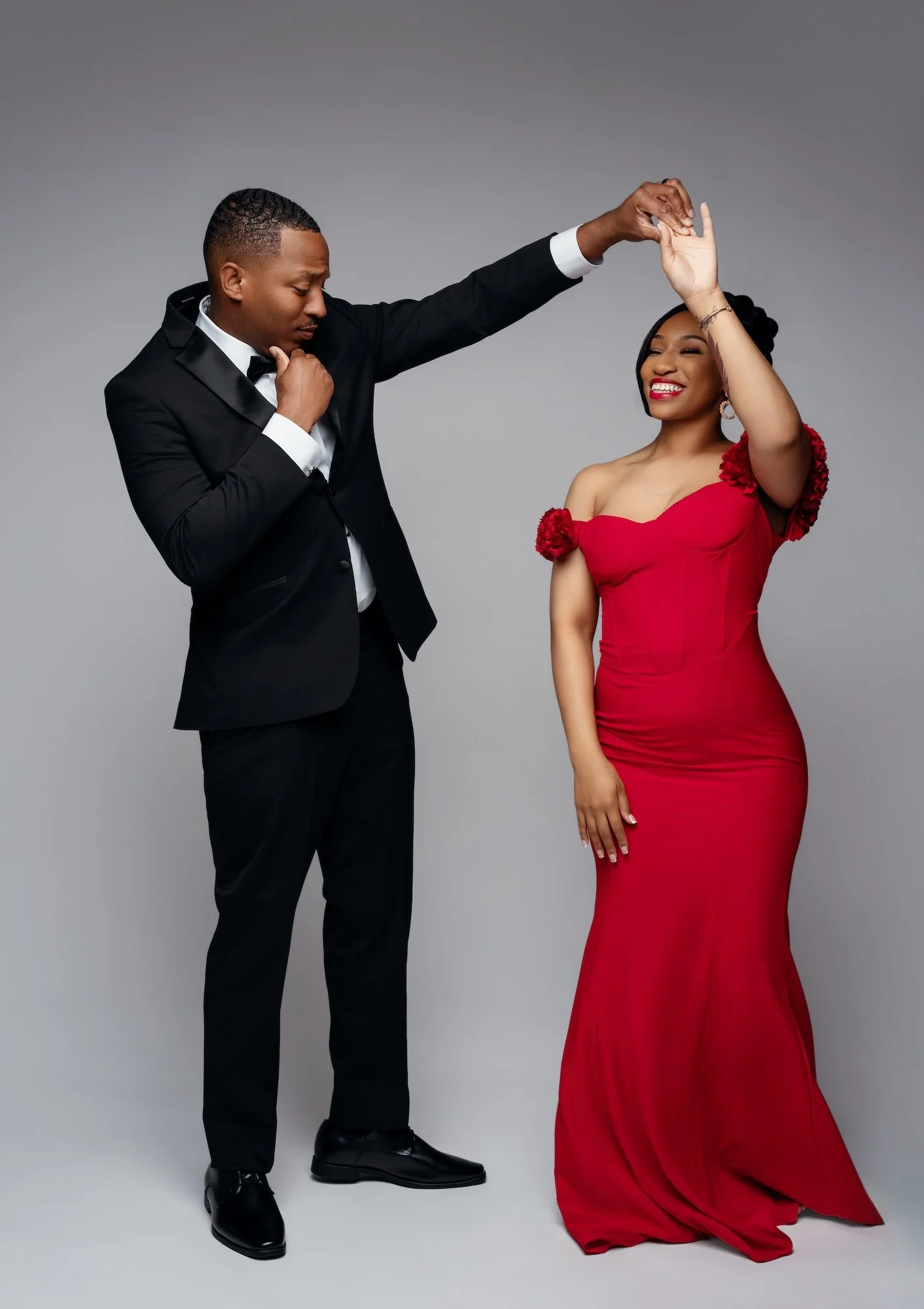 Romantic engagement photo, man spinning woman in red floral dress in dance pose, studio portrait at Filaneyka Photo Studio Chicago