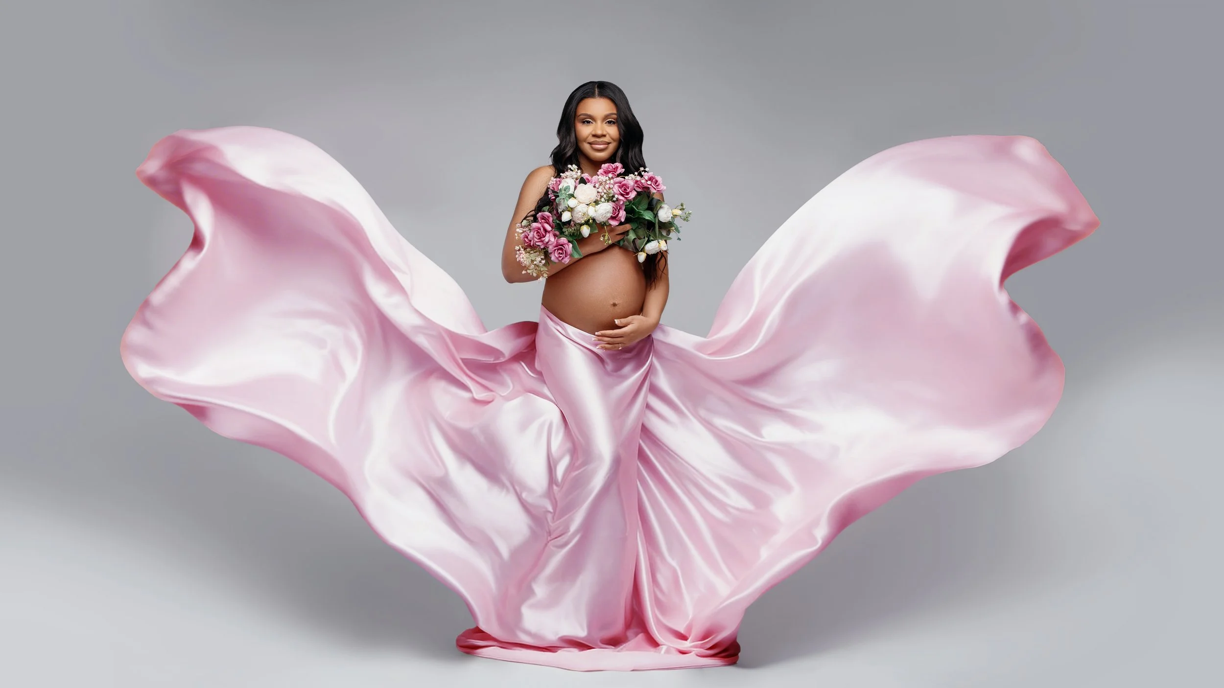 Pregnant woman in pink satin dress with floral bouquet