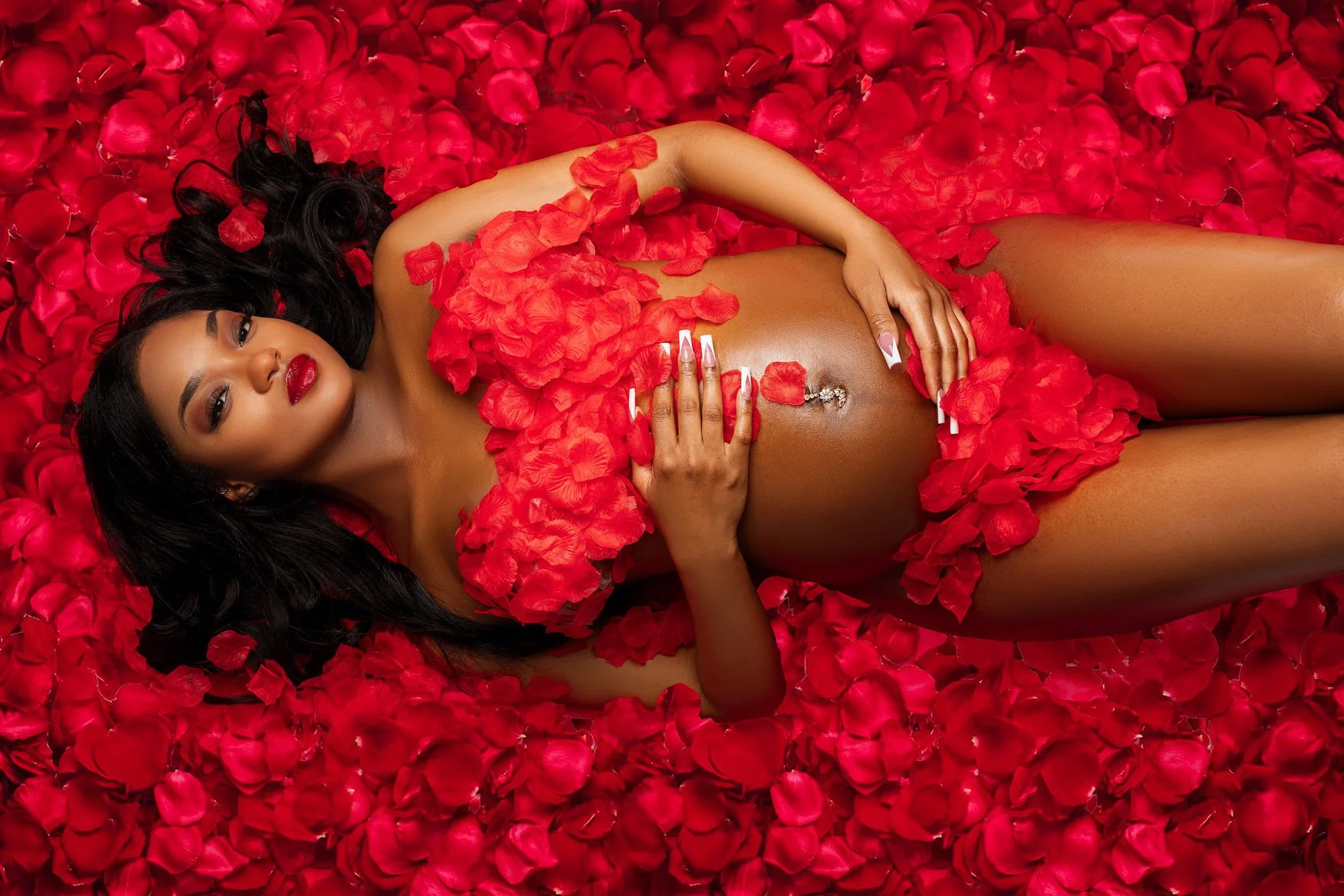 Prenatal photography session with pregnant woman in red rose petals in Chicago - Filaneyka photo studio