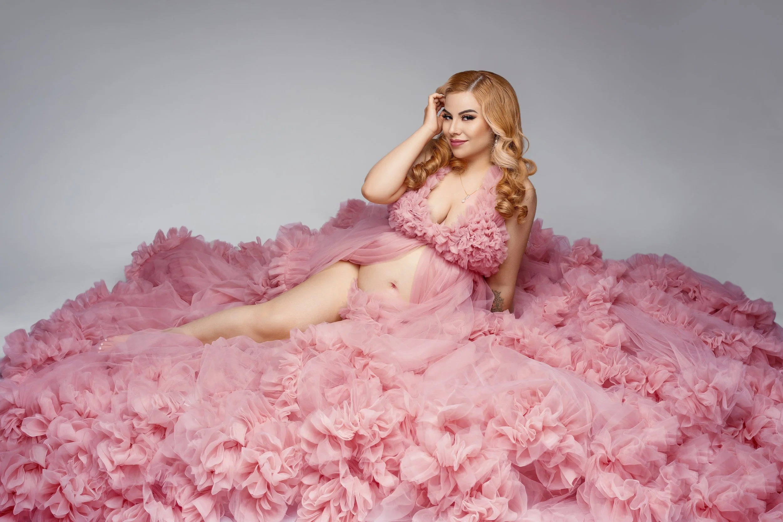 Boutique maternity portrait: pregnant woman in a pink ruffled gown