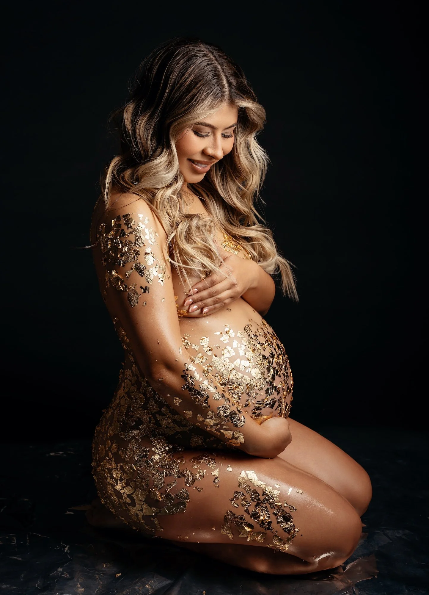 Luxury maternity photoshoot: pregnant woman with dramatic gold body art on her bump