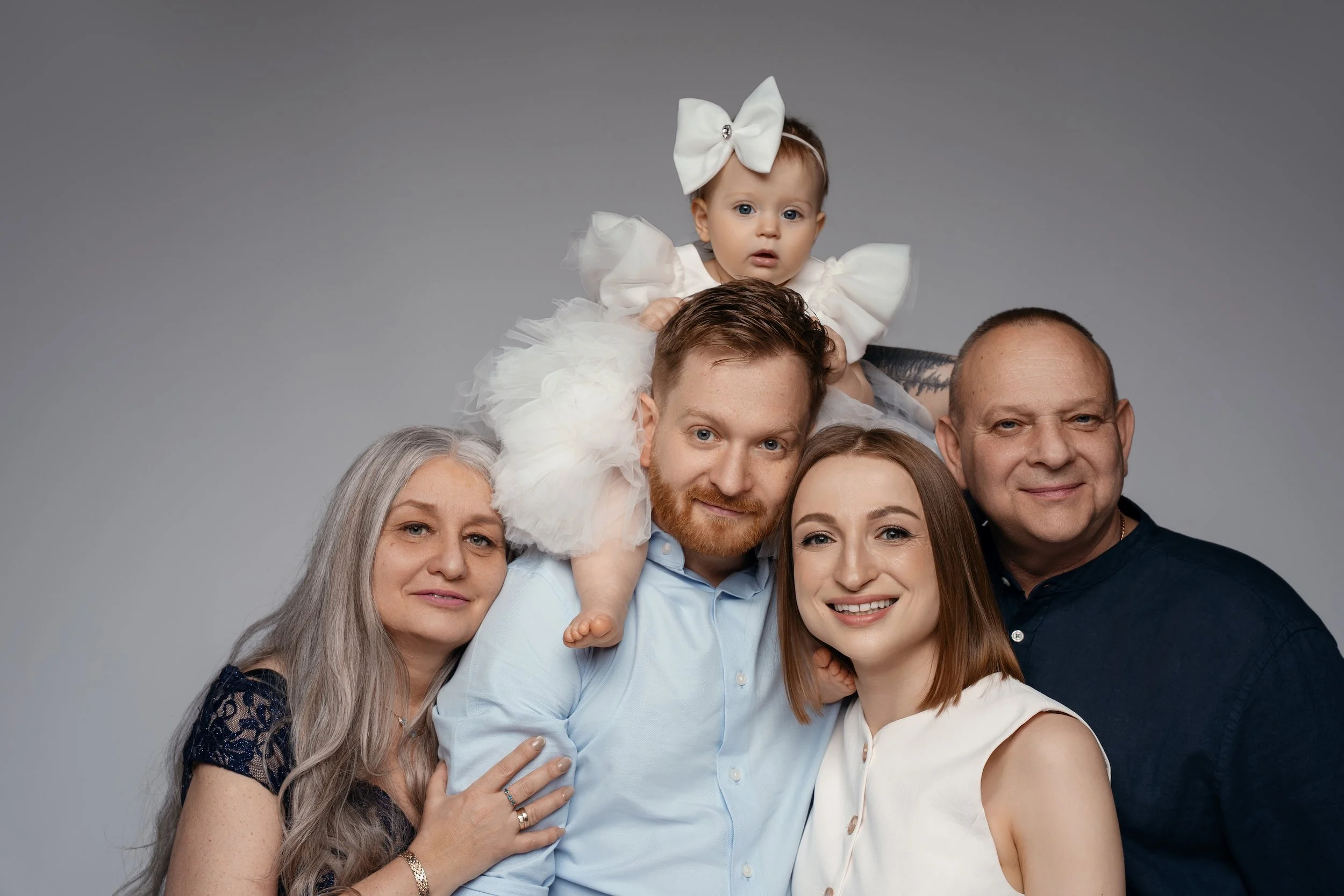 Beautiful extended family studio session in Chicago showing three generations smiling together against a classic grey background.