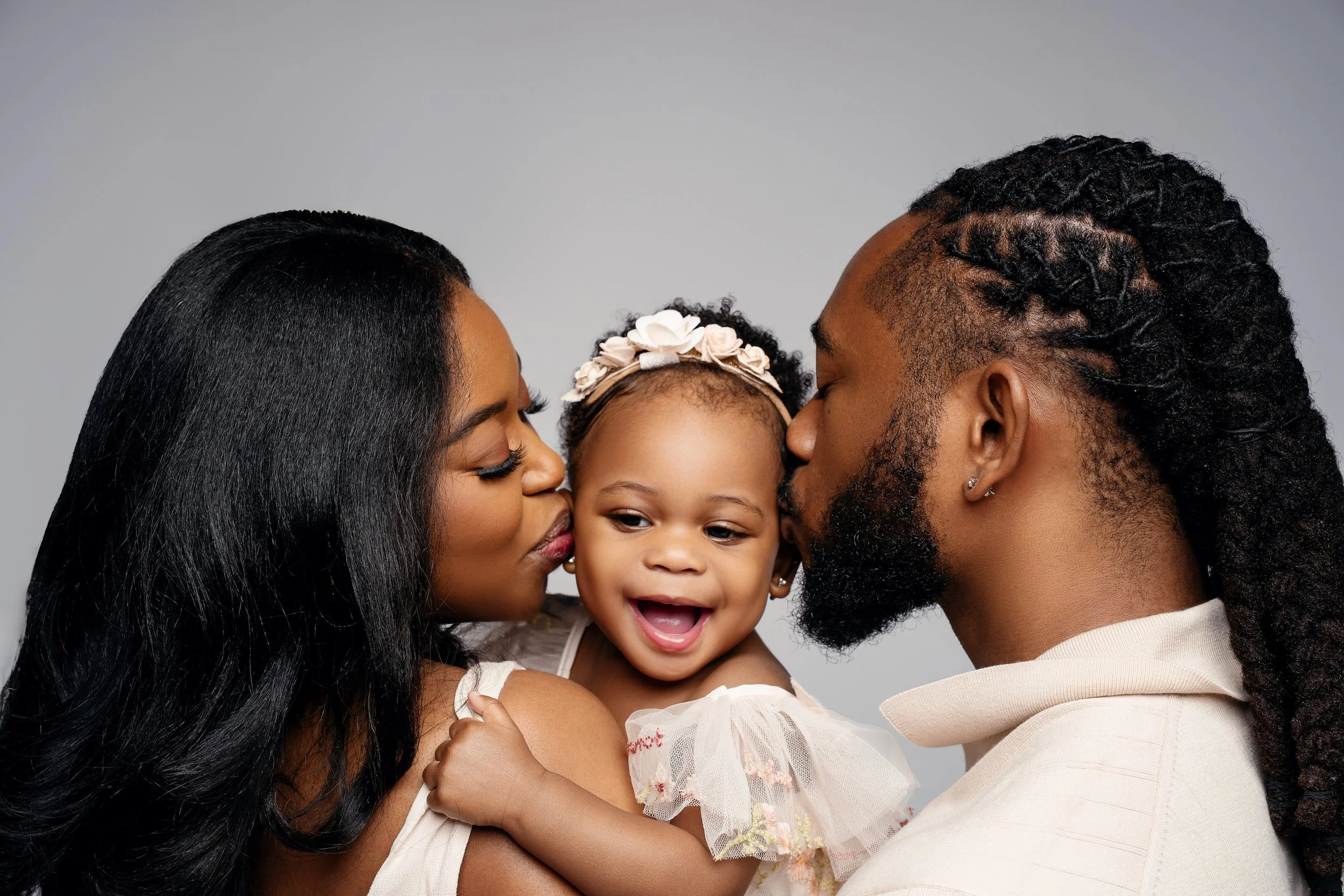 Luxury family photo: parents kissing their baby in the studio