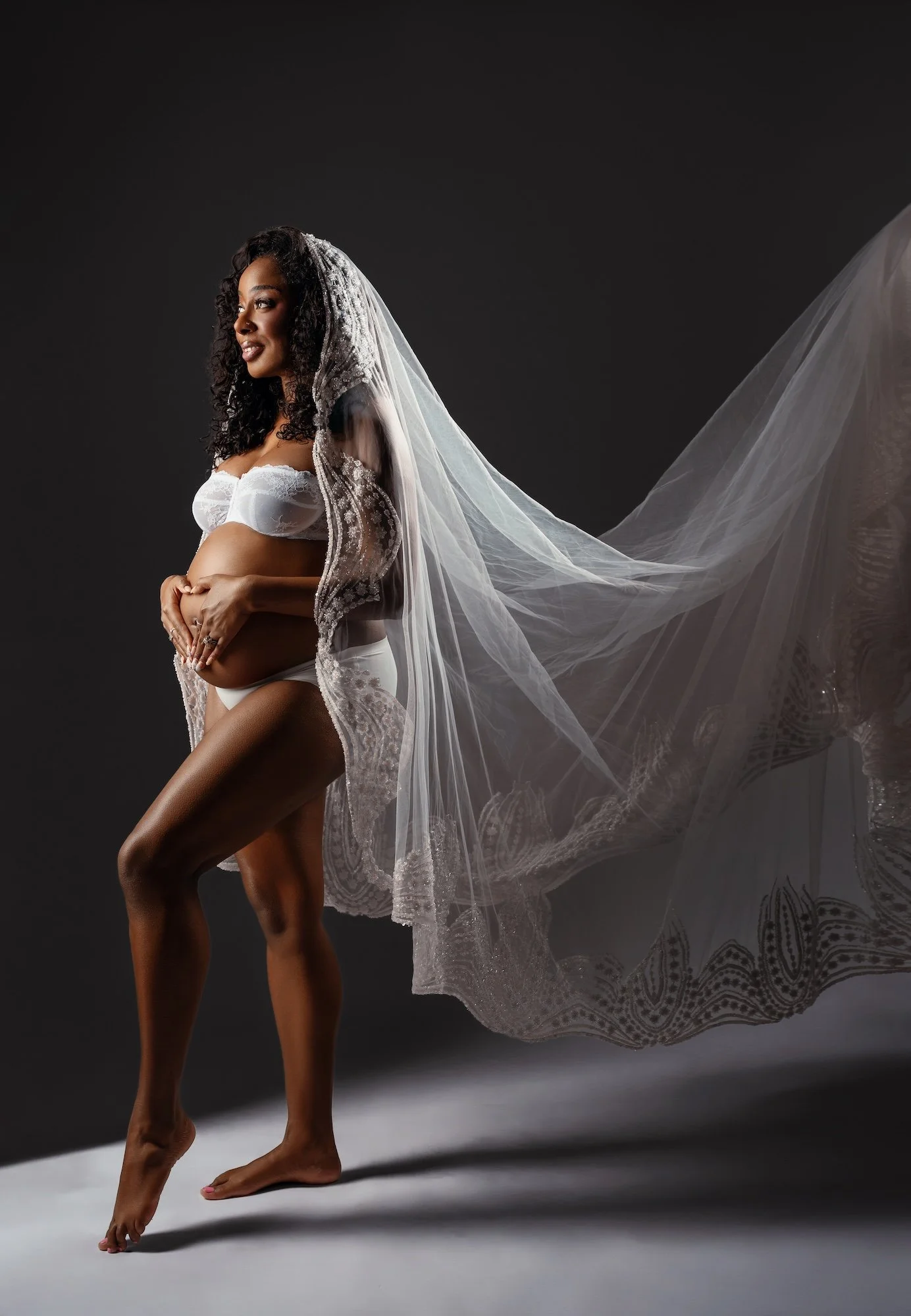 Luxury maternity photoshoot: pregnant woman in a white veil with bridal-style styling