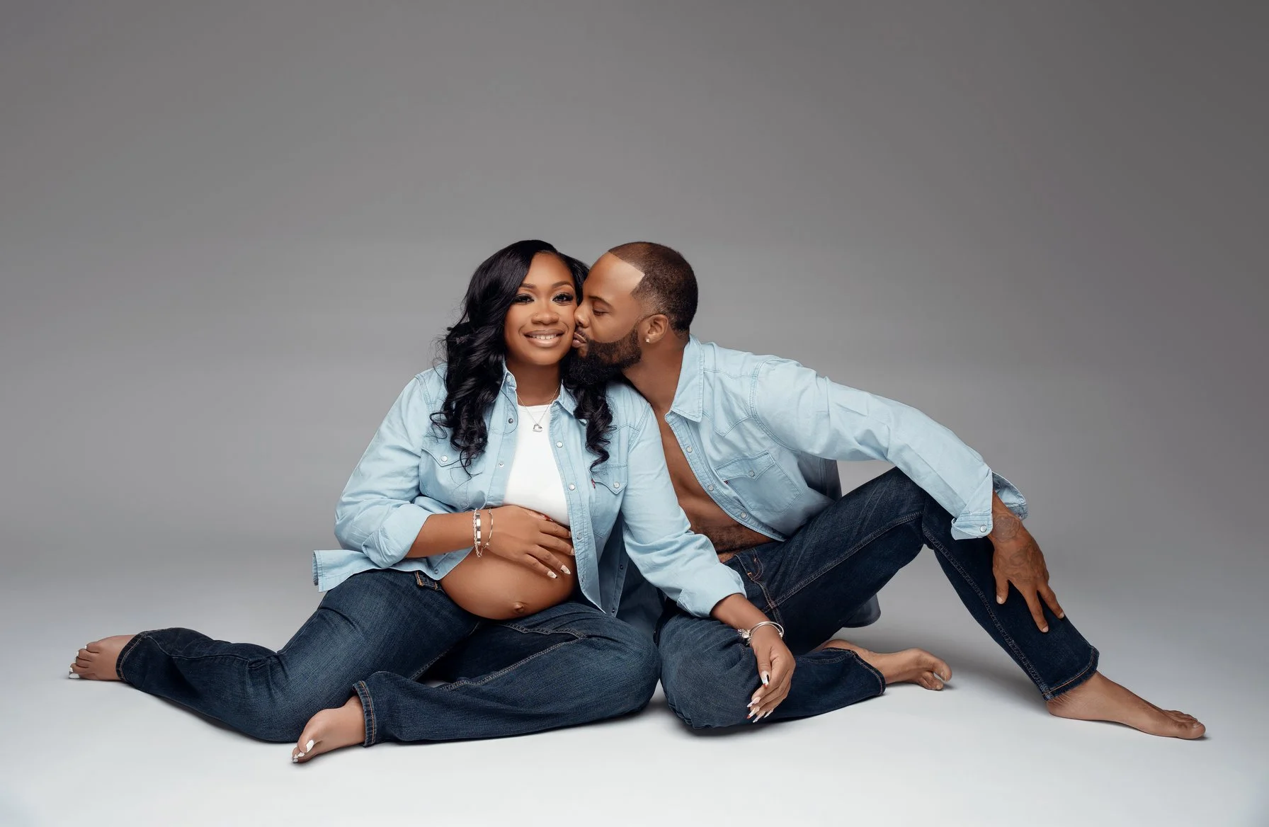 Prenatal photography session with couple sitting kissing pregnant belly in Chicago - Filaneyka photo studio