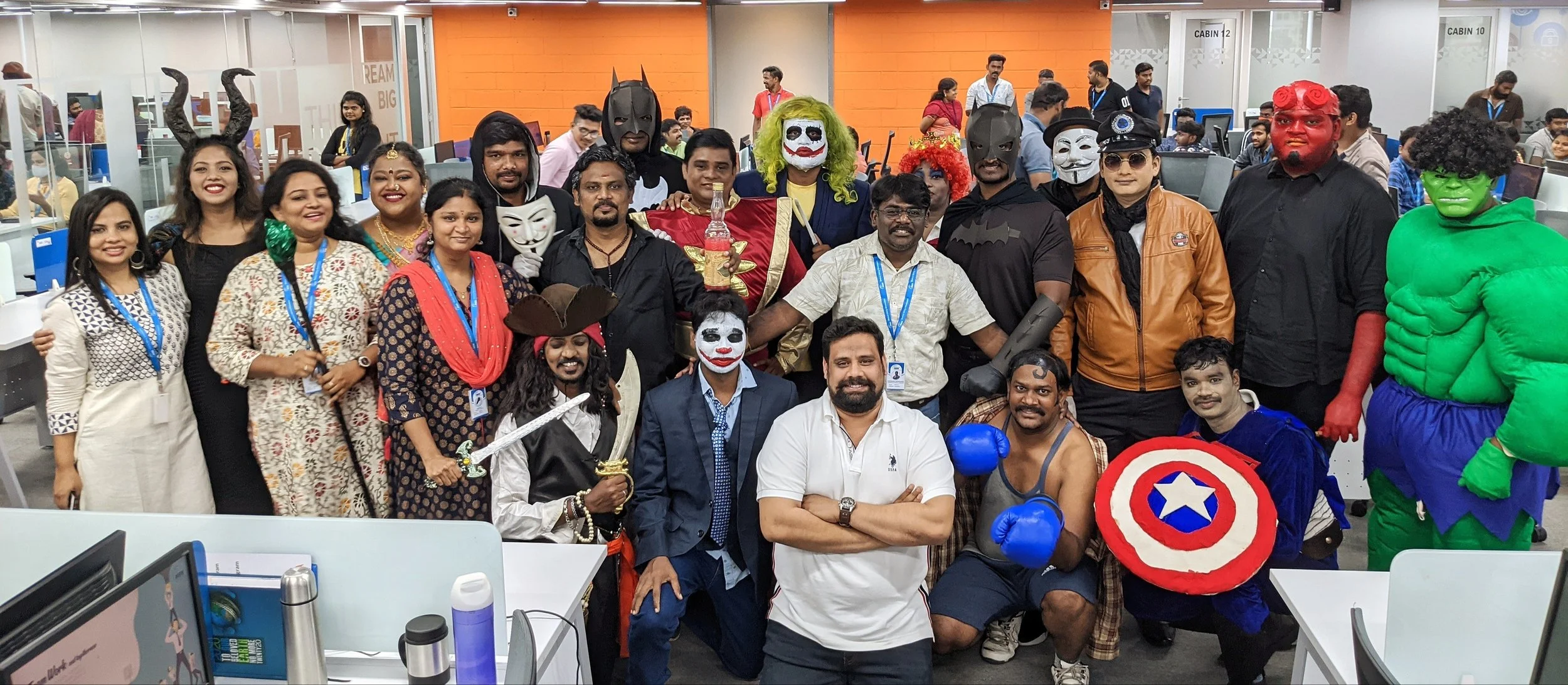 Group of people in costumes celebrating Halloween in an office setting.